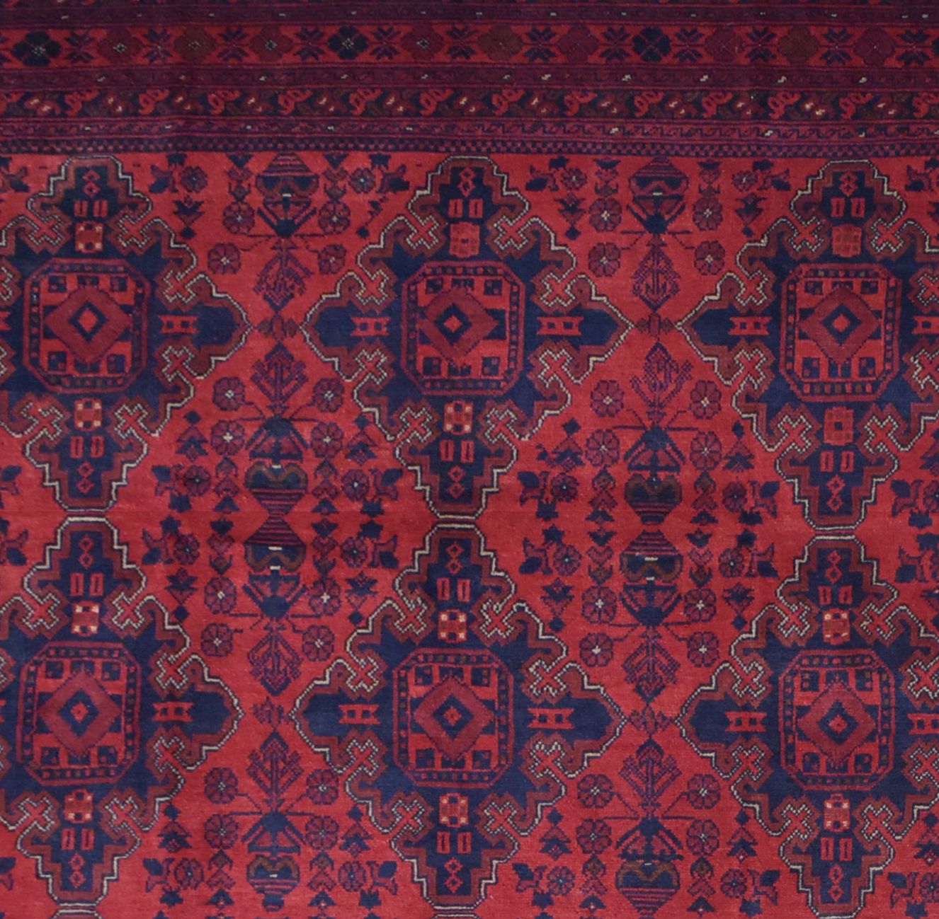 Handmade Afghan Khal Mohammadi rug featuring a deep red field with repeating blue geometric motifs.