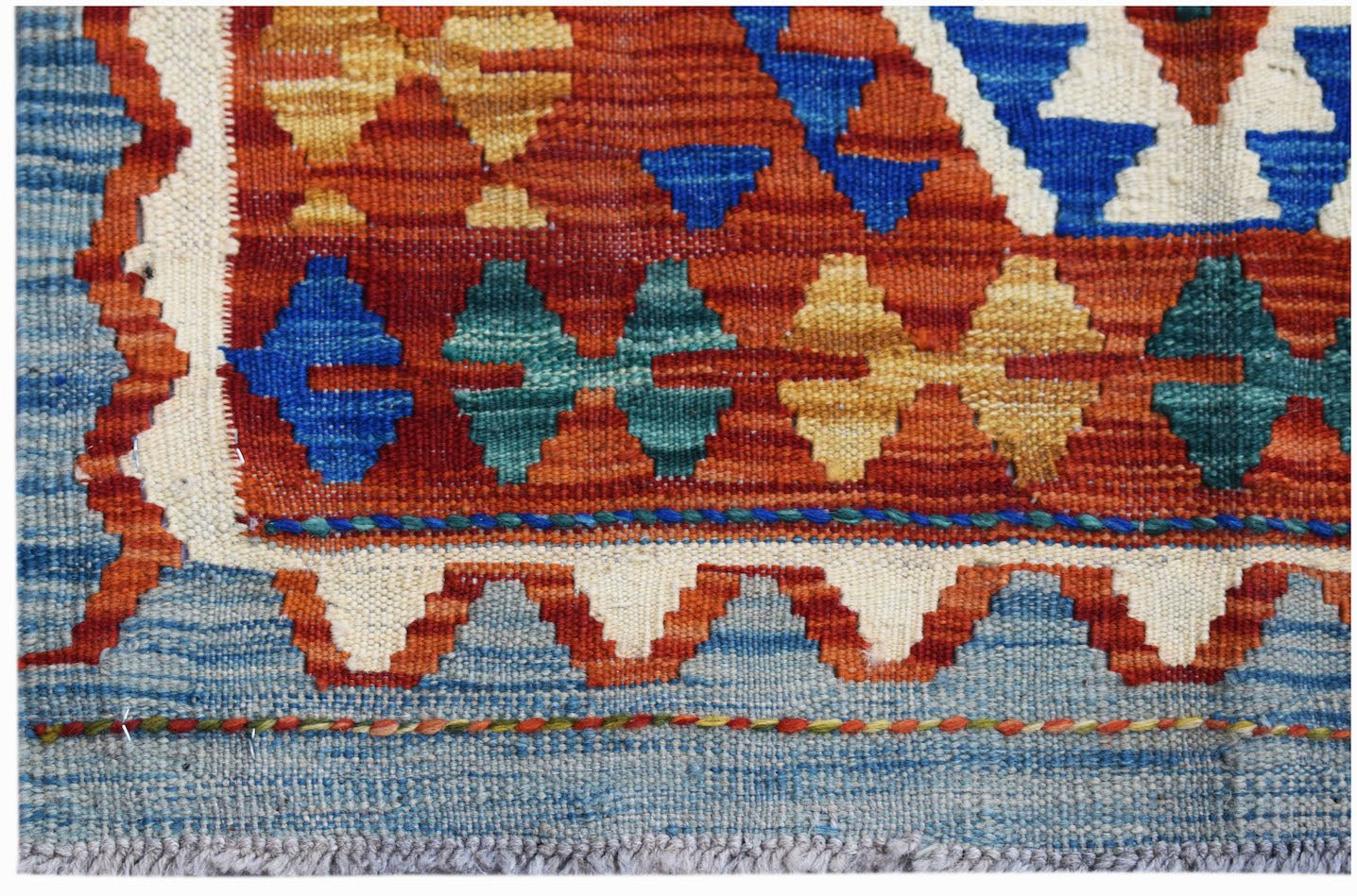 Handwoven Afghan Maimana kilim featuring geometric patterns in vibrant red, blue, and yellow wool.