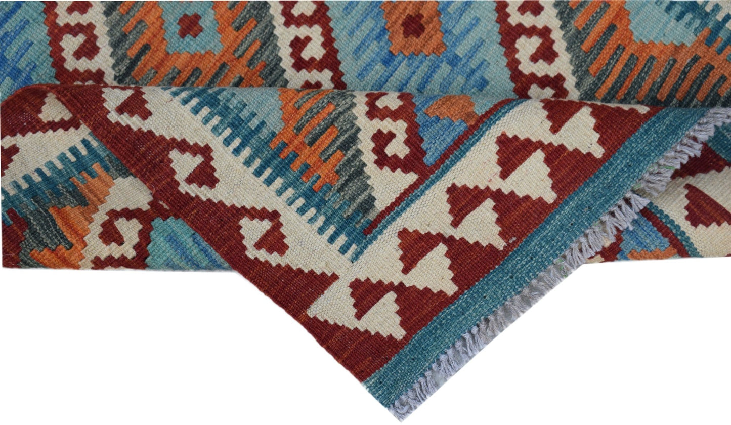 A handmade Afghan Maimana kilim rug featuring geometric patterns in red, blue, and orange wool.