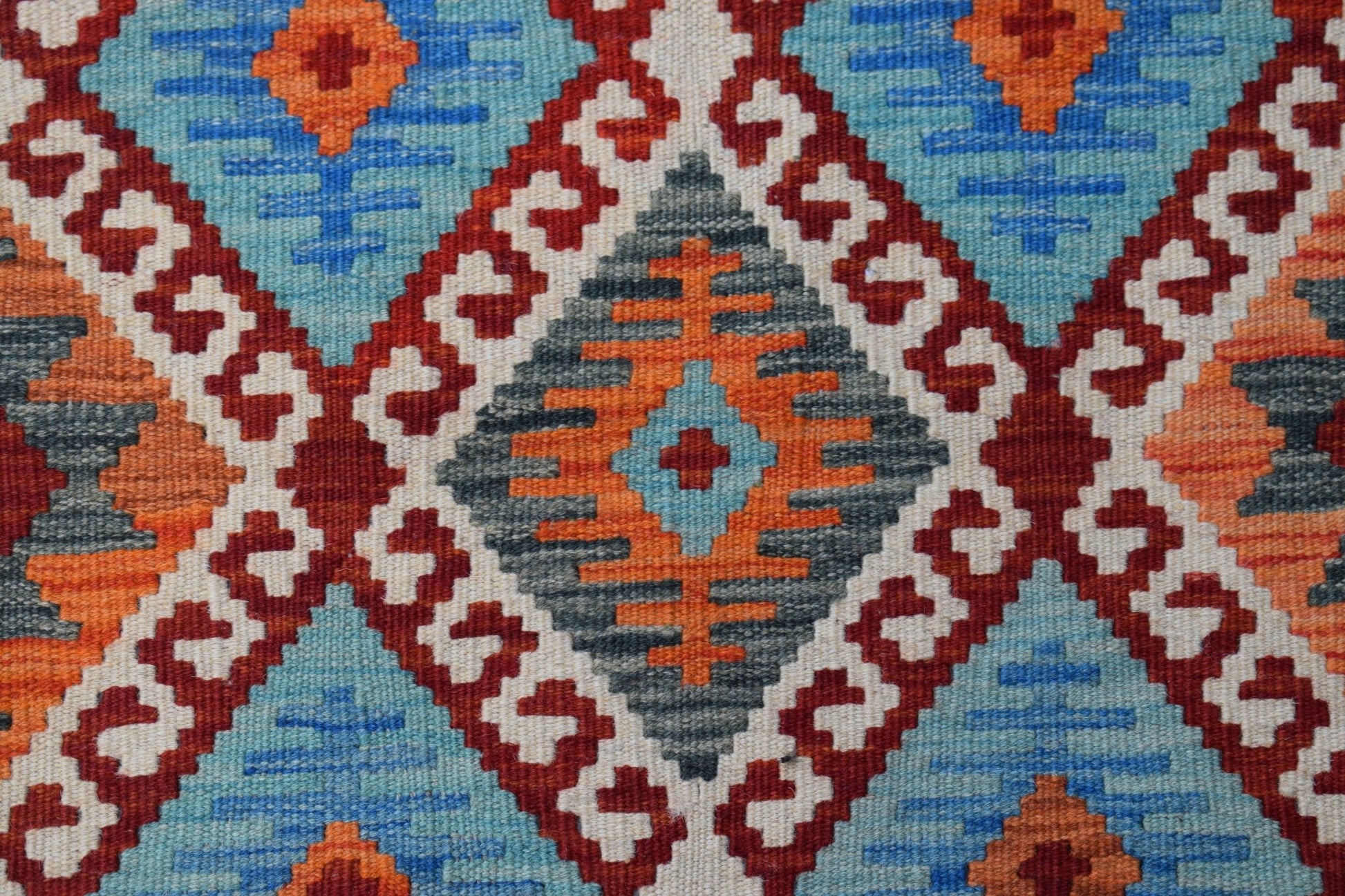 Handwoven Afghan Maimana kilim featuring a geometric diamond pattern in blue, orange, and red.