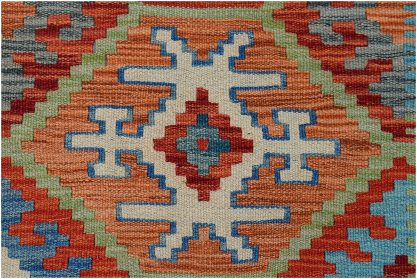 A handmade Afghan Maimana kilim featuring a geometric pattern in orange, blue, and green wool.