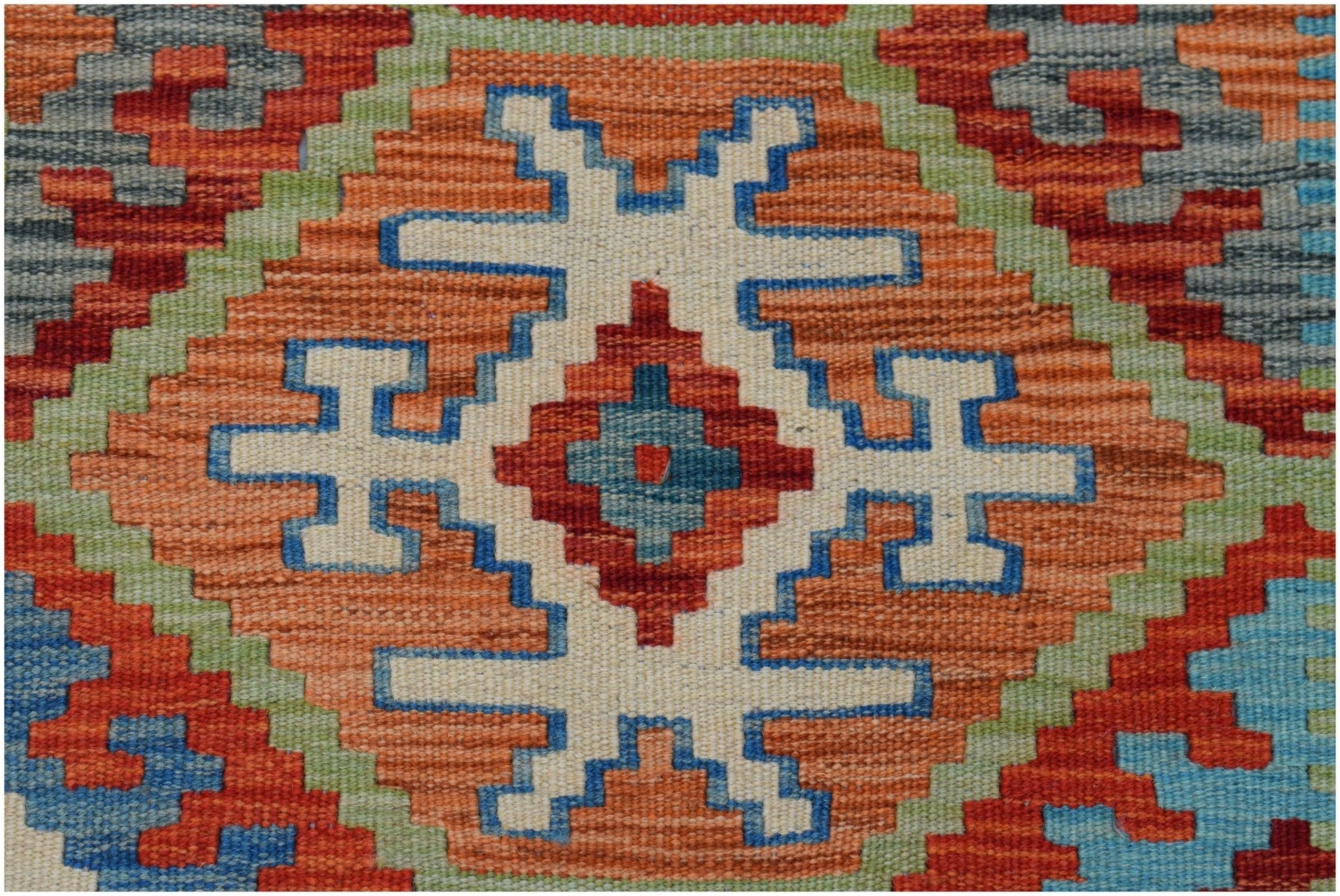 A handmade Afghan Maimana kilim featuring a geometric pattern in orange, blue, and green wool.
