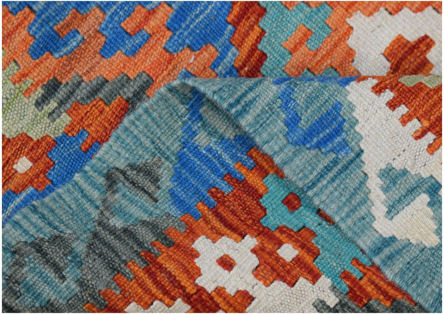 A close-up of a handmade Afghan Maimana kilim featuring vibrant geometric patterns in wool.