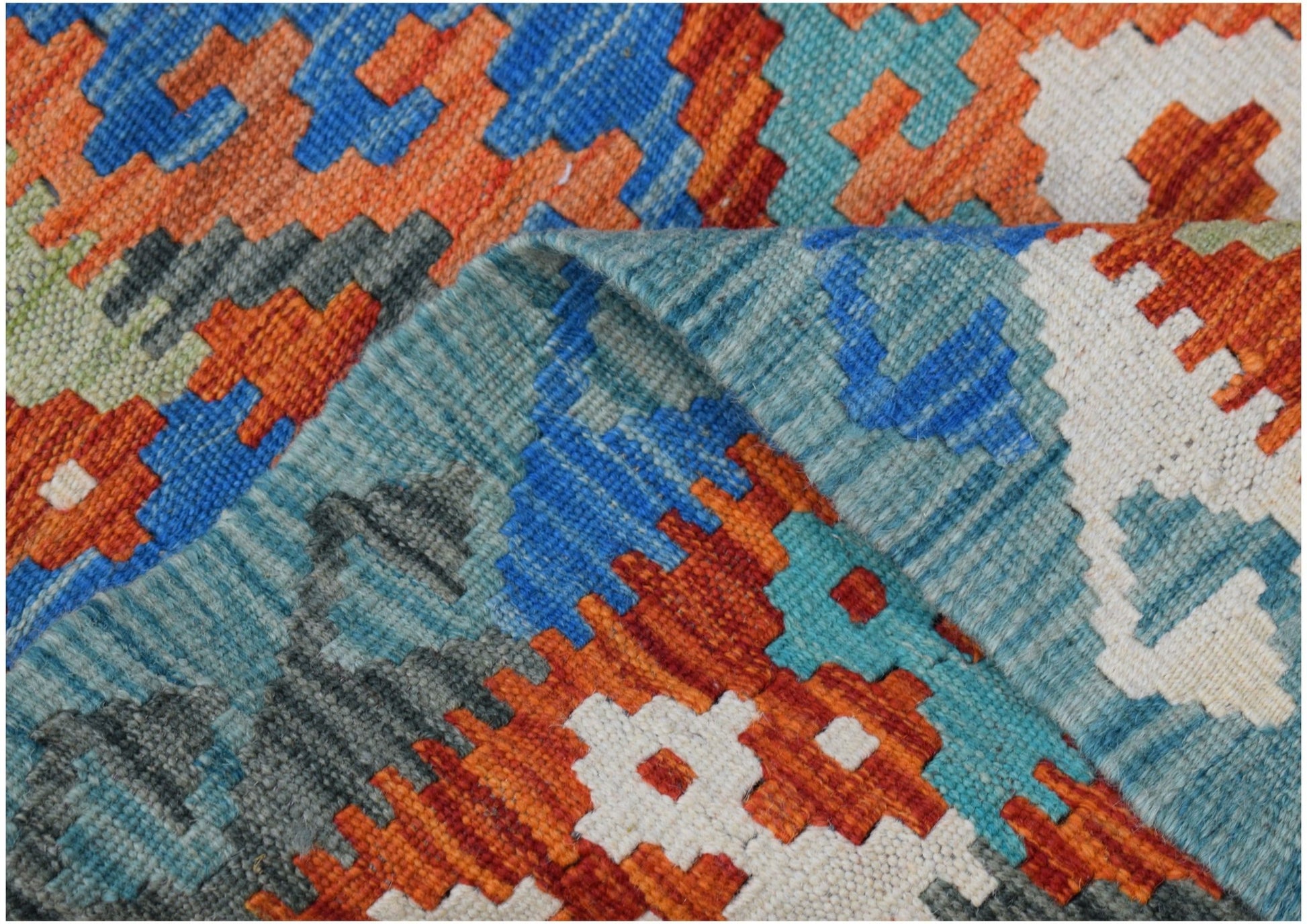 A close-up of a handmade Afghan Maimana kilim featuring vibrant geometric patterns in wool.