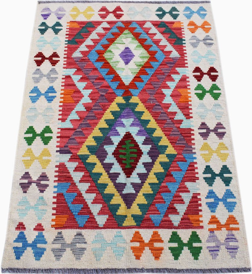 Handwoven Afghan Maimana kilim rug featuring a colorful geometric diamond pattern on a cream base.