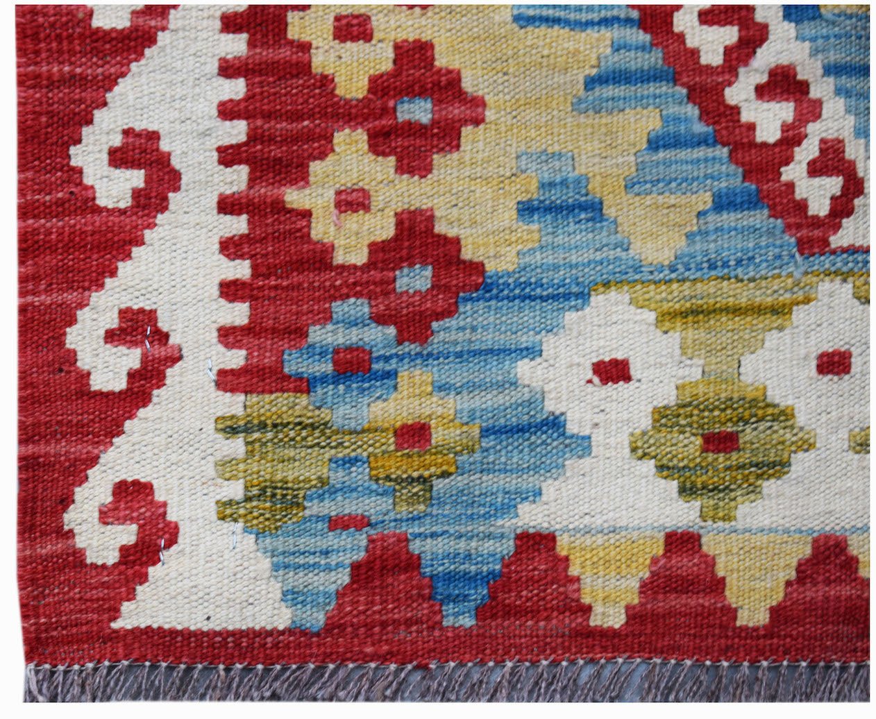 Handwoven Afghan Maimana kilim rug featuring a geometric pattern in red, blue, and yellow wool.