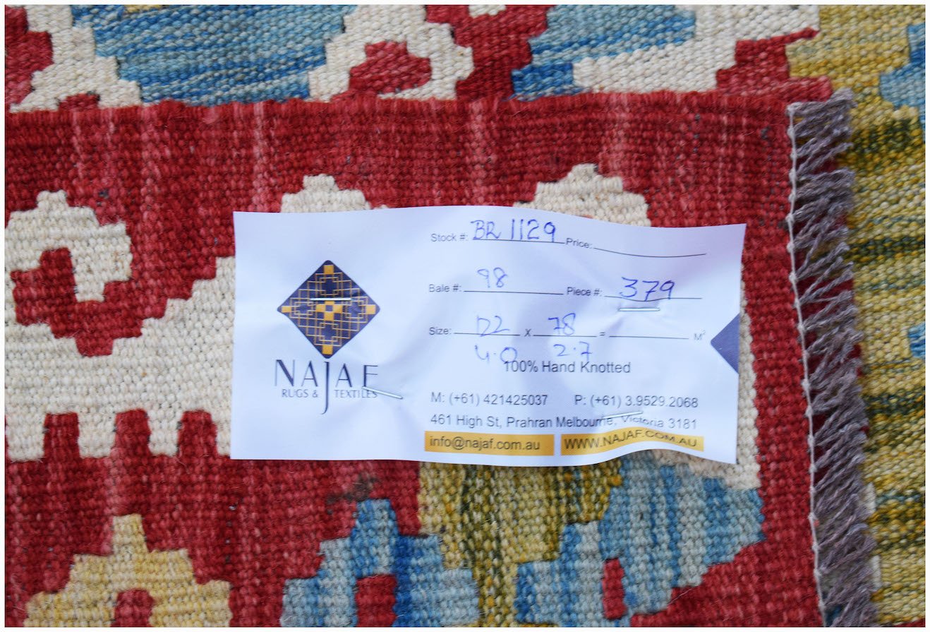 A close-up of a handmade Afghan Maimana Kilim featuring a vibrant geometric pattern in wool.