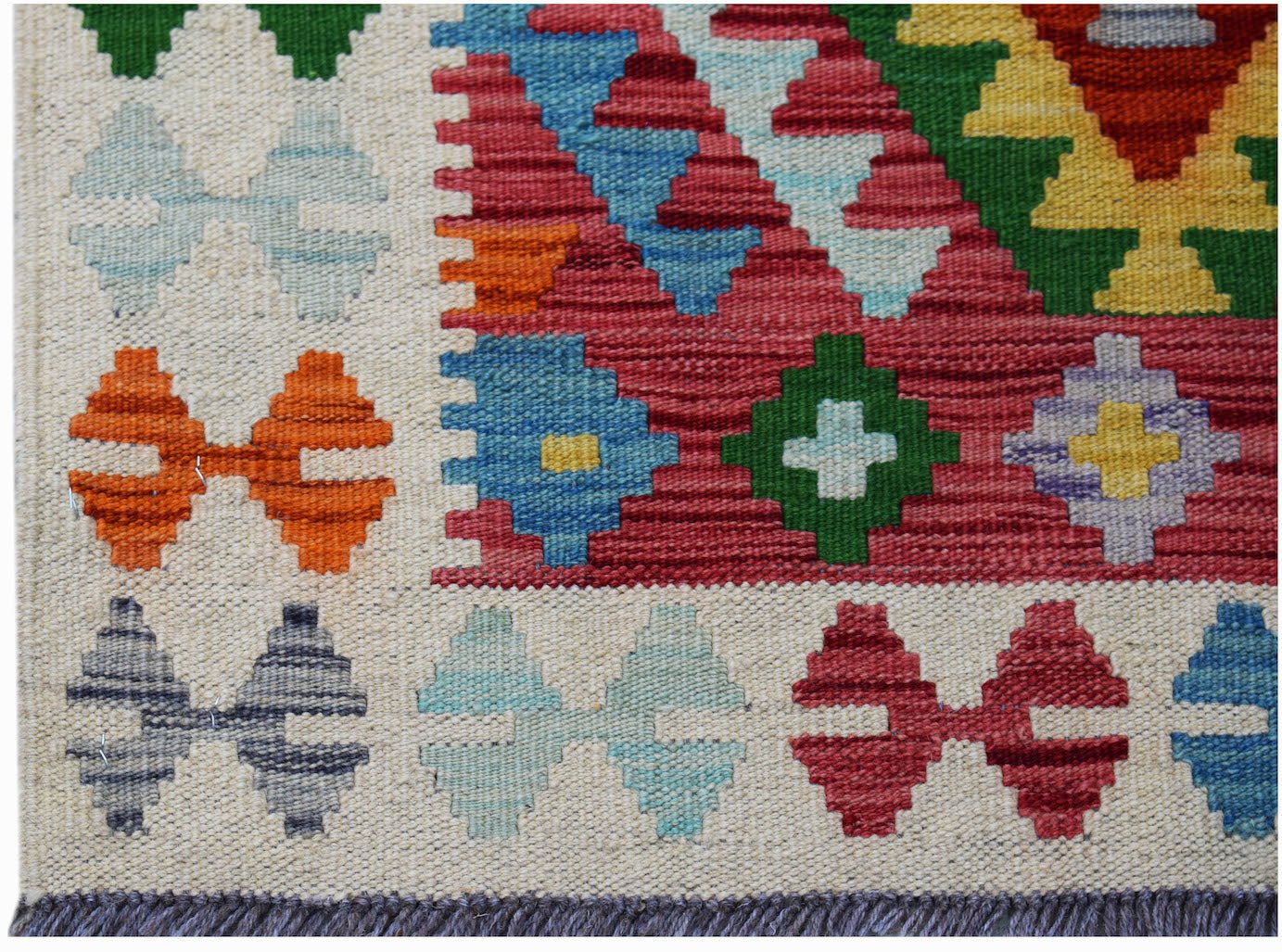 Handwoven Afghan Maimana kilim rug featuring a colorful geometric pattern on a cream background.