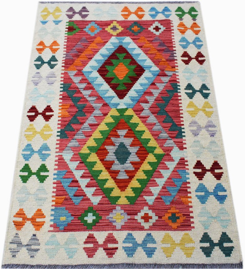 Handwoven Afghan Maimana kilim rug featuring a vibrant geometric pattern on a red background.