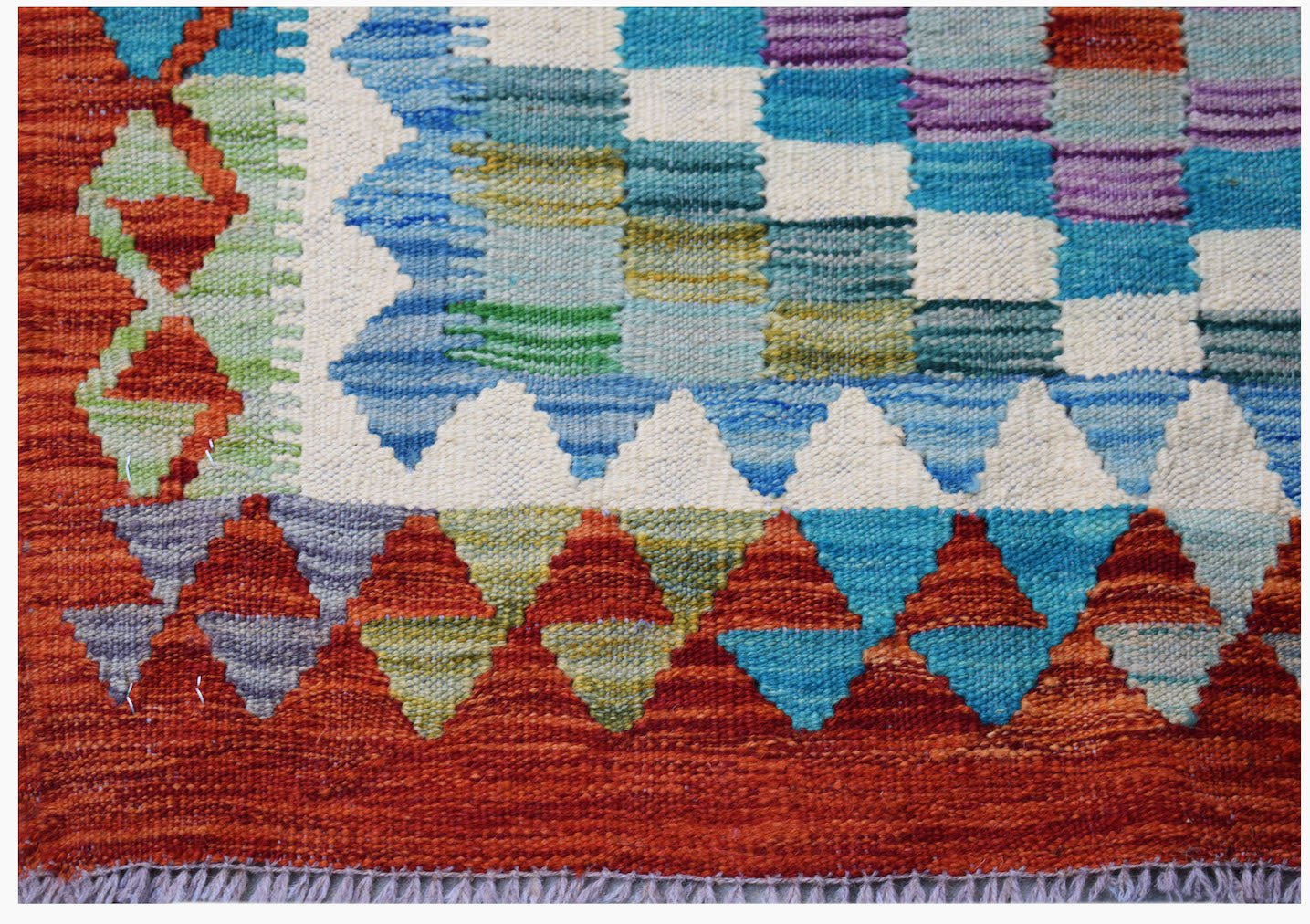 Handwoven Afghan Maimana kilim rug featuring a geometric pattern in vibrant multicolored wool.