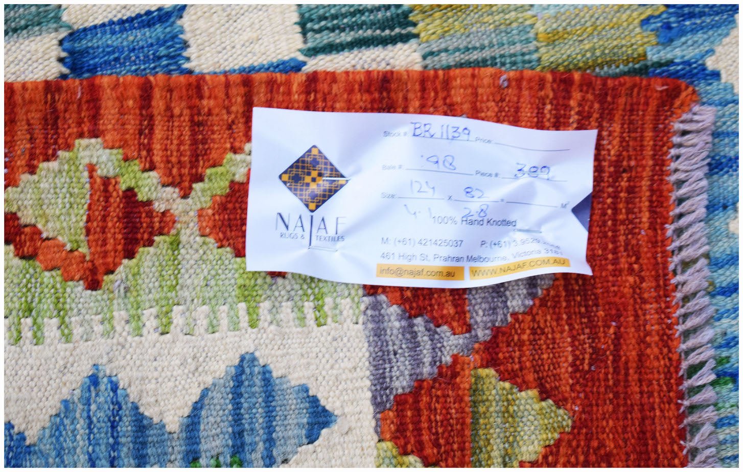 A handwoven Afghan Maimana kilim featuring a vibrant geometric pattern in blue, green, and orange.