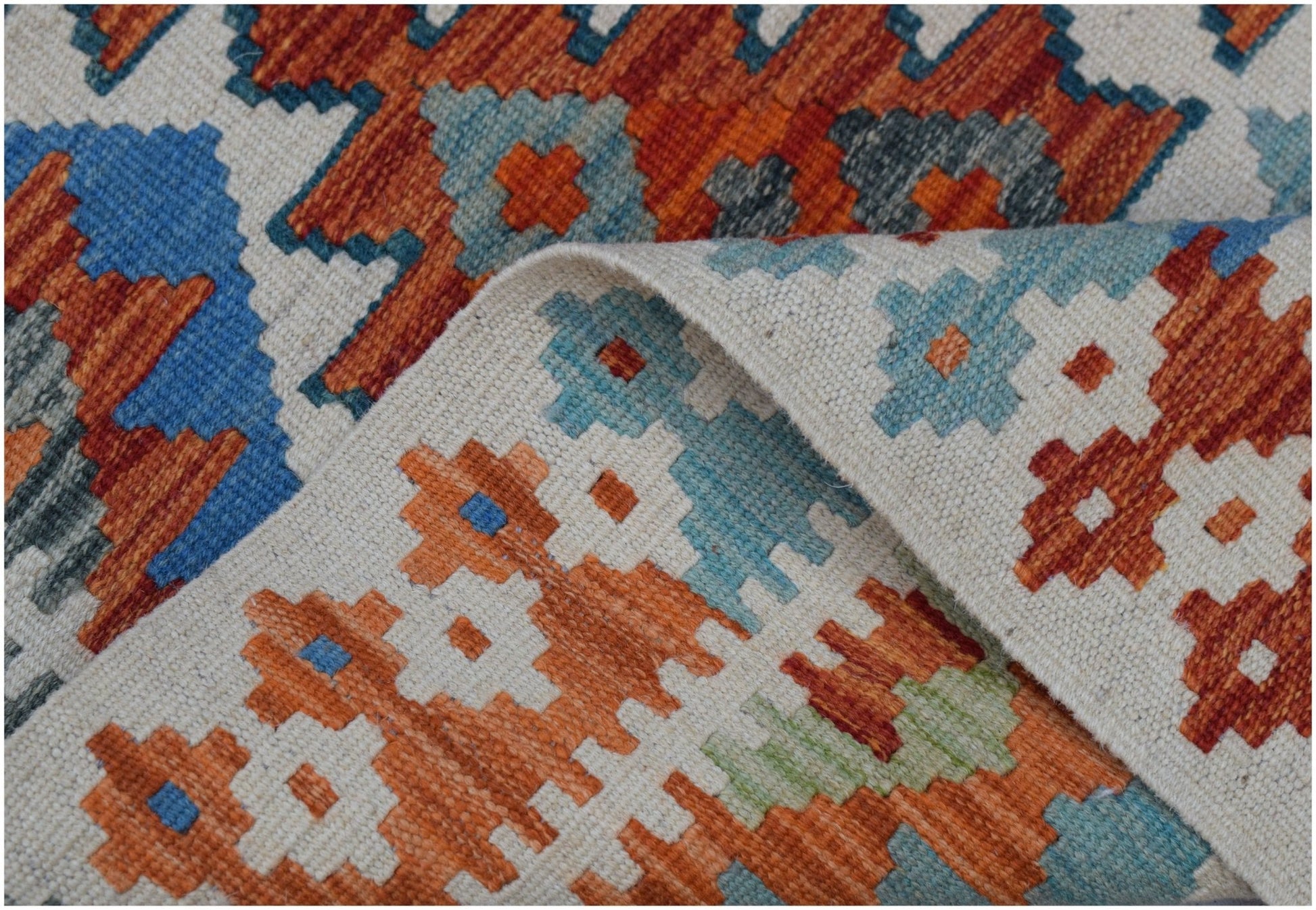 A handmade Afghan Maimana kilim rug featuring a geometric pattern in orange, blue, and cream wool.