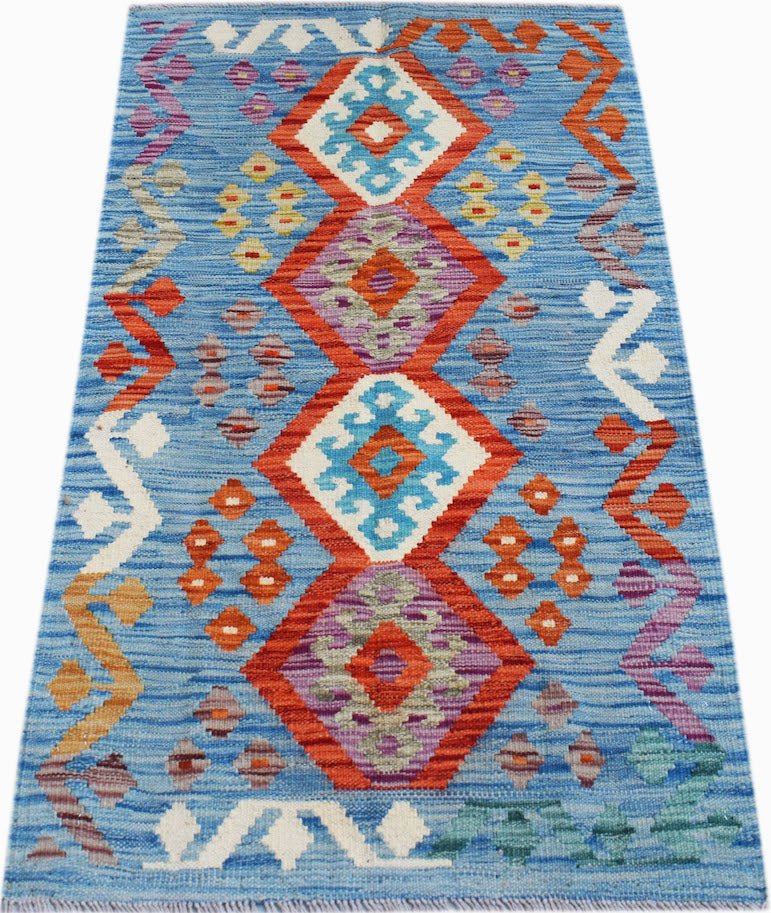 A handmade Afghan Maimana kilim rug featuring geometric diamond patterns in blue, orange, and purple.