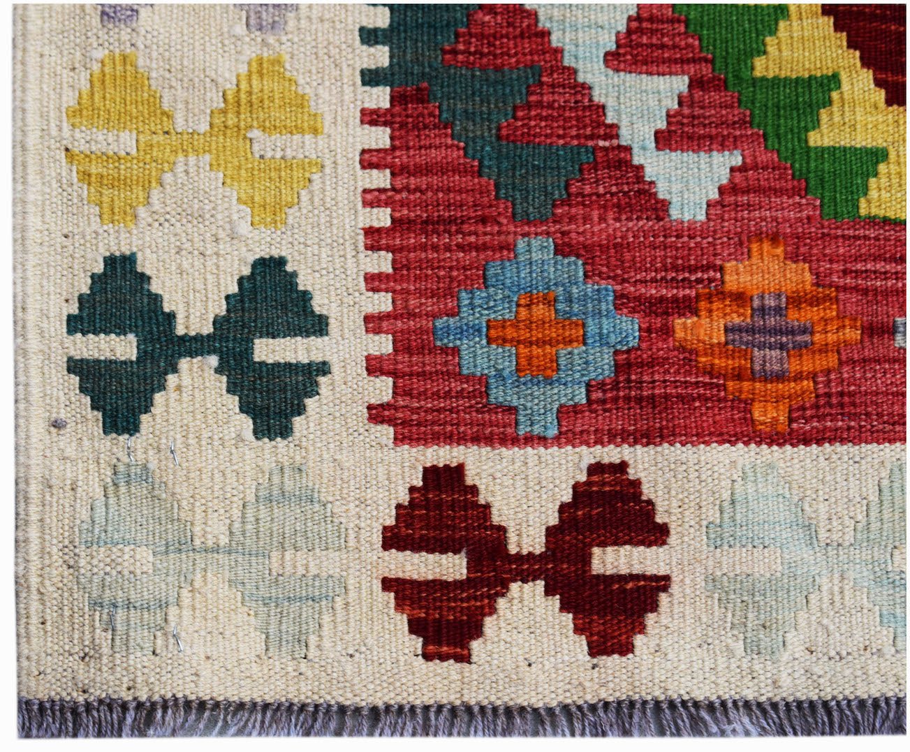 Handwoven Afghan Maimana kilim rug featuring a geometric pattern in vibrant, multi-colored wool.