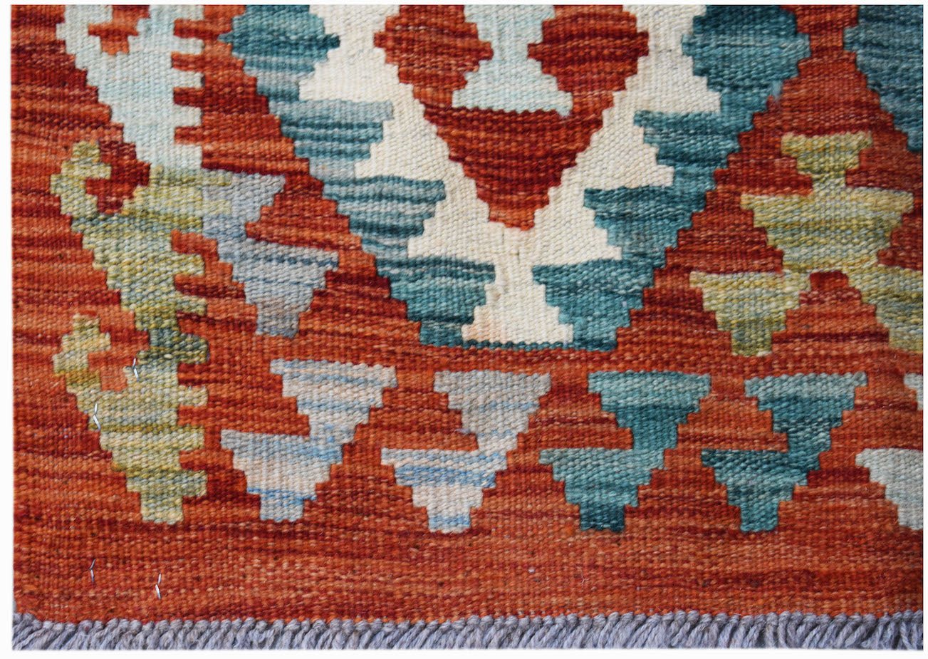 Handwoven Afghan Maimana kilim rug featuring a geometric pattern in rust, blue, and cream tones.