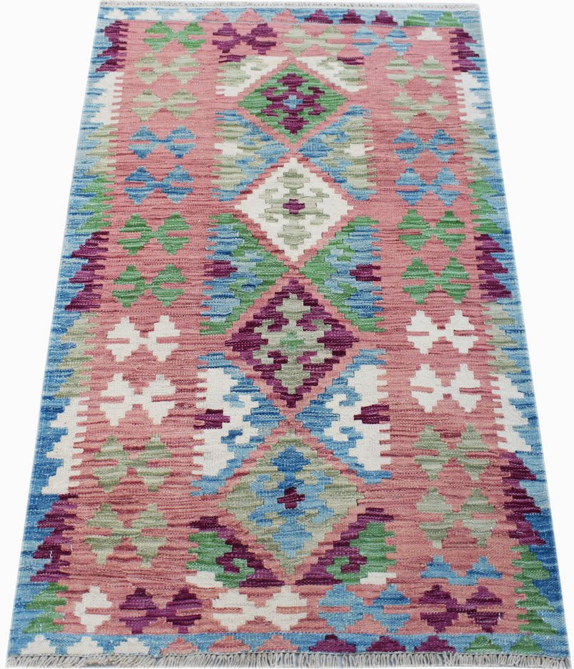 Handwoven Afghan Maimana kilim rug featuring a geometric diamond pattern in pink, blue, and green.