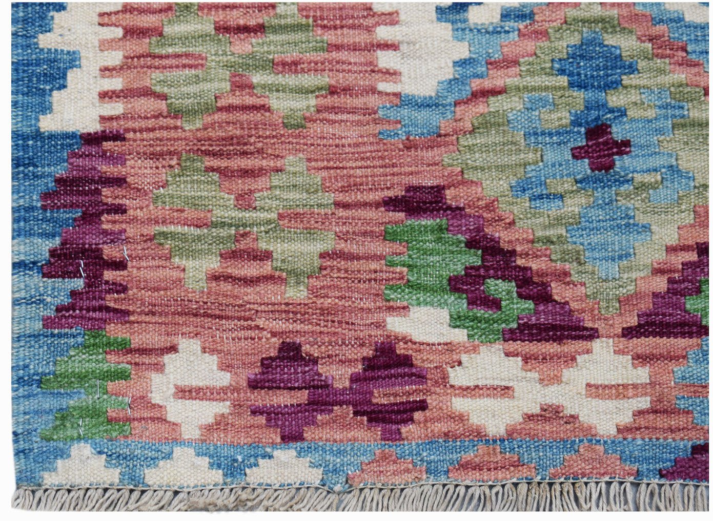A handmade Afghan Maimana kilim rug featuring a geometric pattern in blue, pink, green, and white.