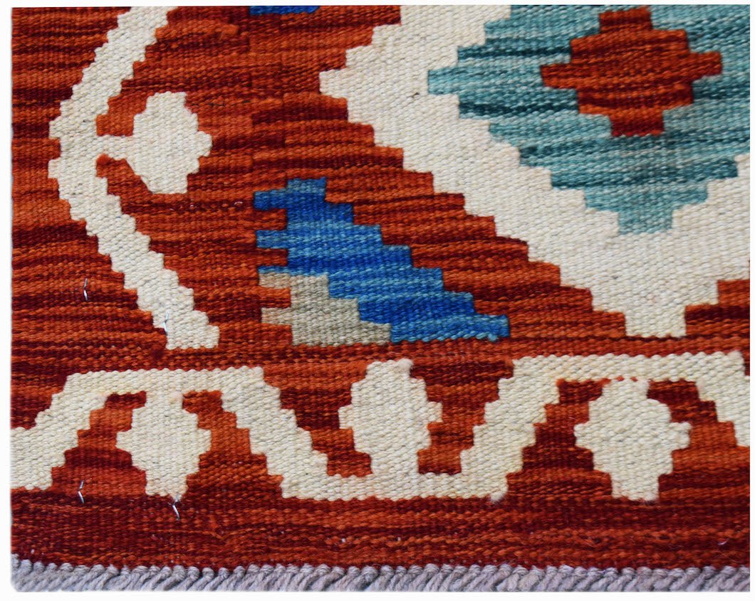Handwoven Afghan Maimana kilim featuring a geometric pattern in rust, cream, and blue wool.