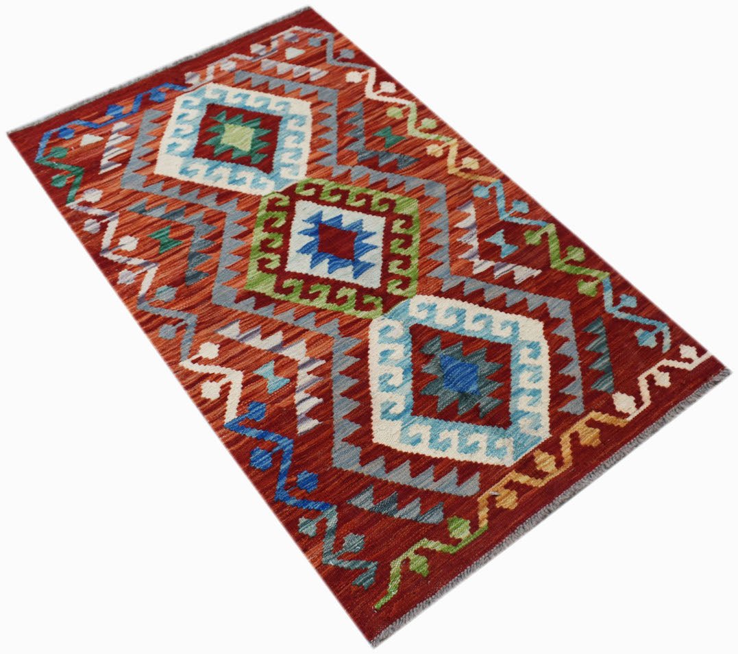 A rectangular Afghan Maimana kilim rug featuring geometric diamond patterns in vibrant colors.