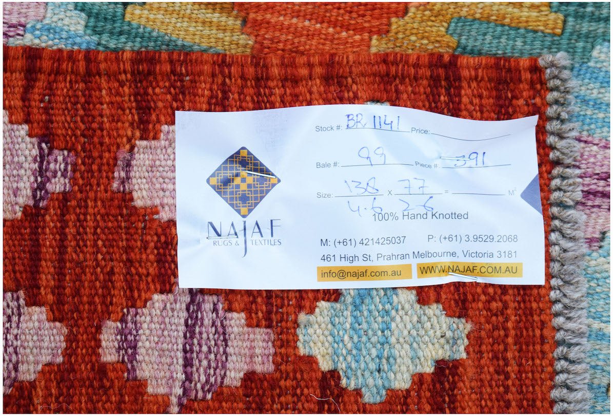A handwoven Afghan Maimana Kilim featuring a geometric pattern in vibrant red, blue, and pink tones.