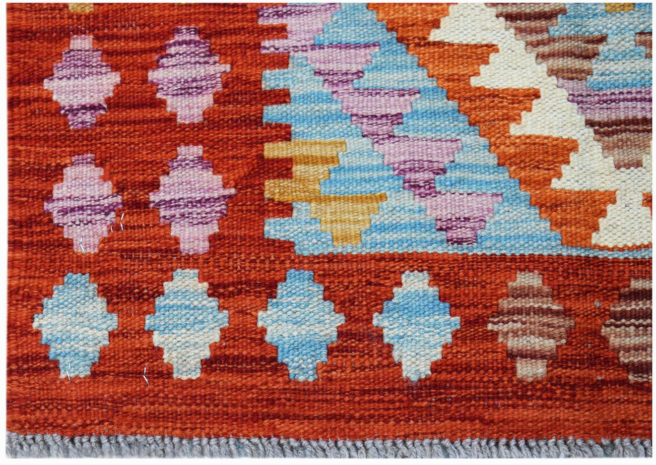 Handwoven Afghan Maimana kilim featuring geometric patterns in vibrant orange, blue, and purple.