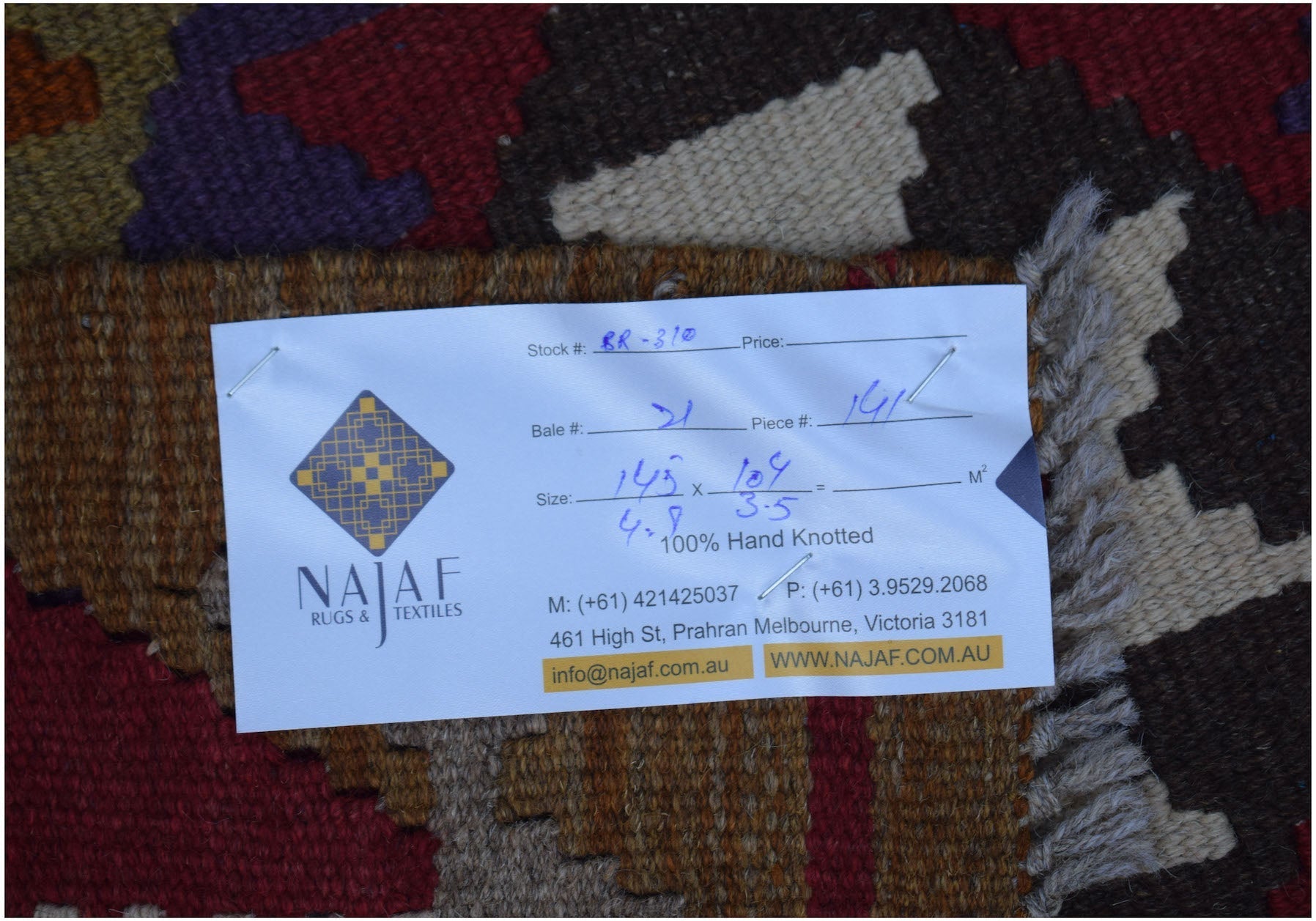 An Afghan Maimana Kilim rug featuring a geometric pattern in rich red, brown, and purple tones.