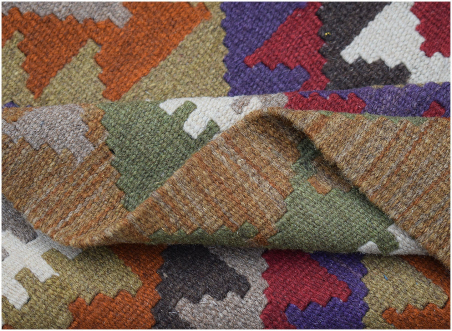 A handwoven Afghan Maimana kilim rug featuring a geometric pattern in rich, multicolored wool.