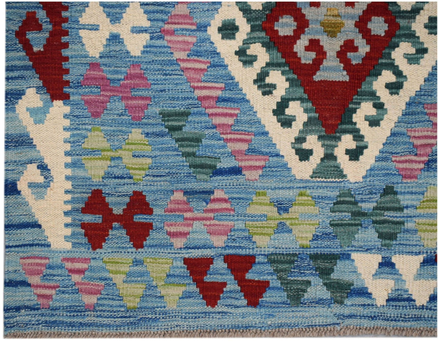 Handwoven Afghan Maimana kilim featuring a blue background with geometric patterns in wool.