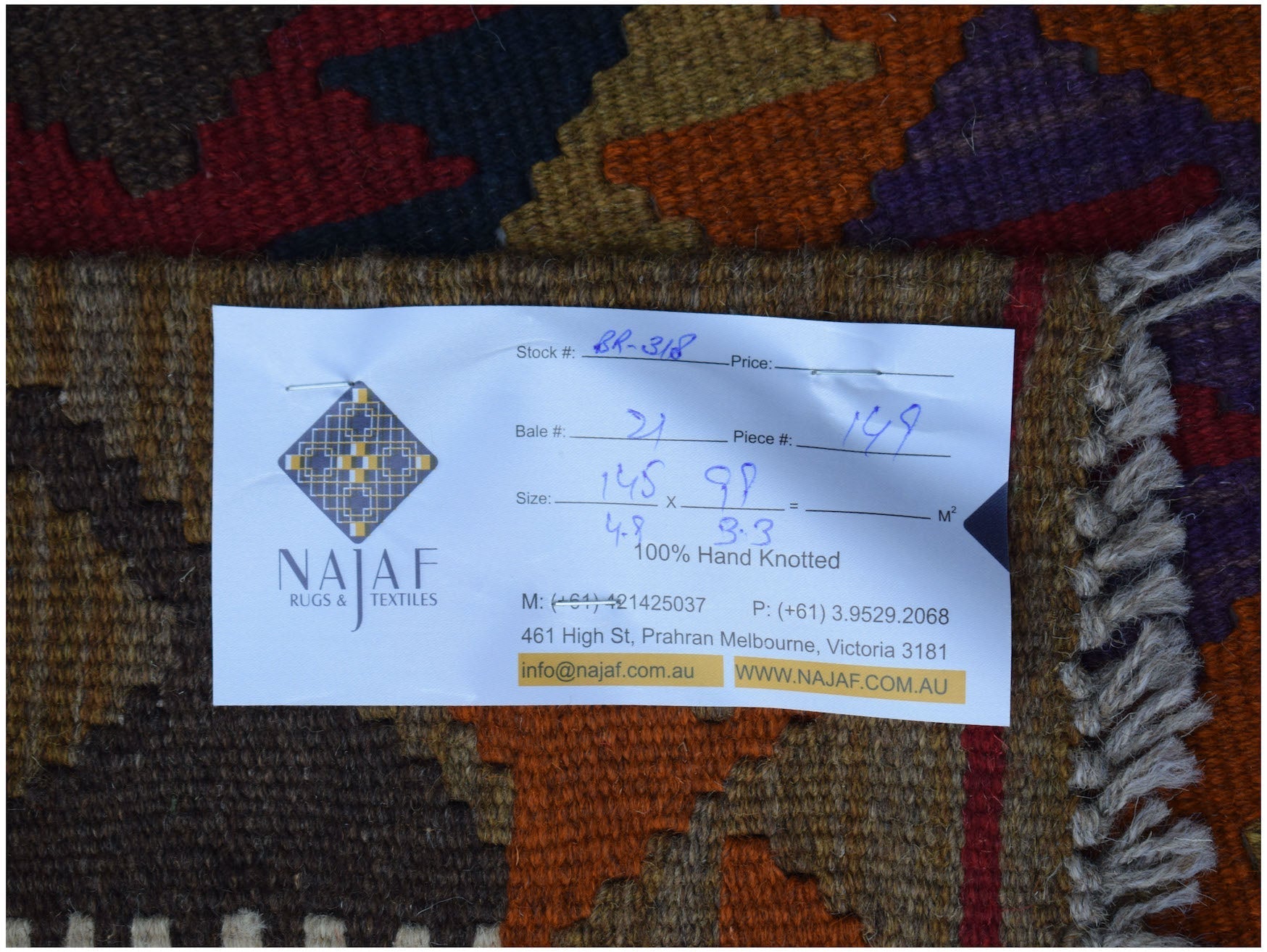 A handwoven Afghan Maimana kilim featuring a geometric pattern in rich, warm earth tones.