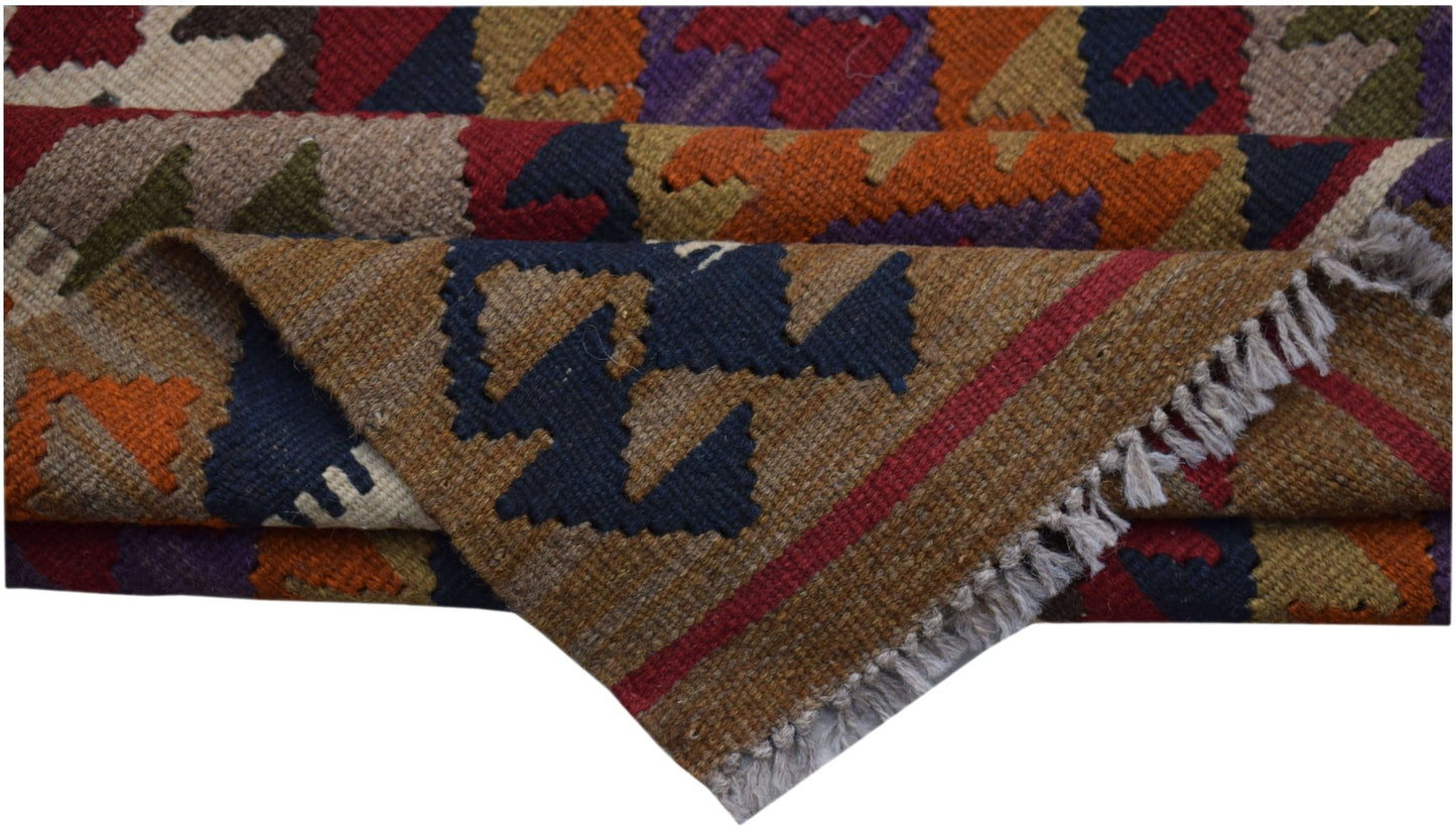 A handwoven Afghan Maimana kilim rug featuring a geometric pattern in rich, multicolored wool.