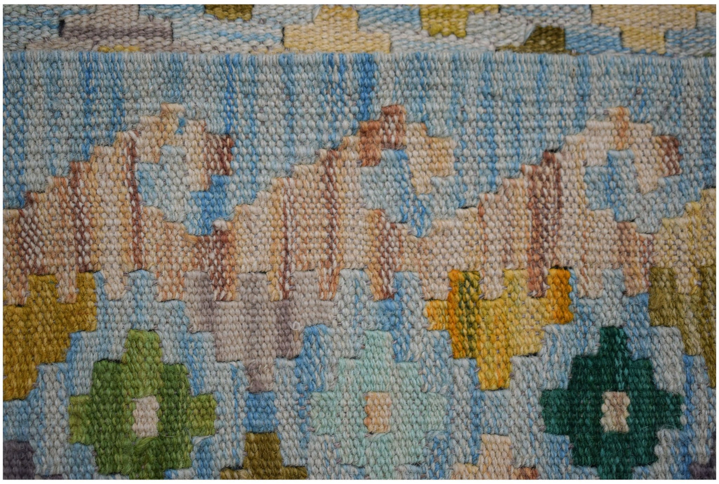A handwoven Afghan Maimana kilim featuring a geometric pattern in blue, green, and tan wool.