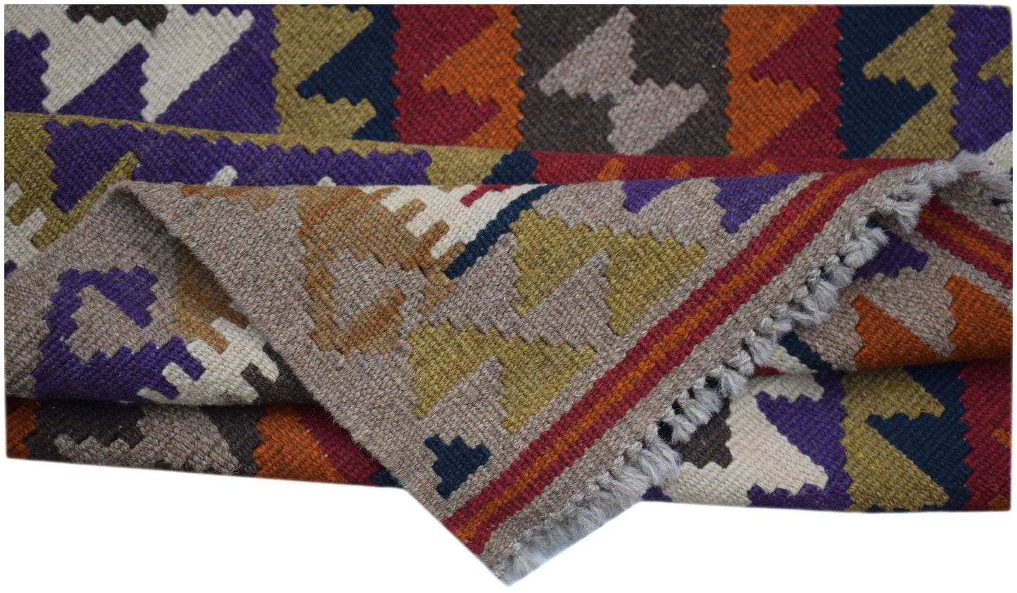 A handmade Afghan Maimana kilim rug featuring a colorful geometric pattern and flatweave texture.