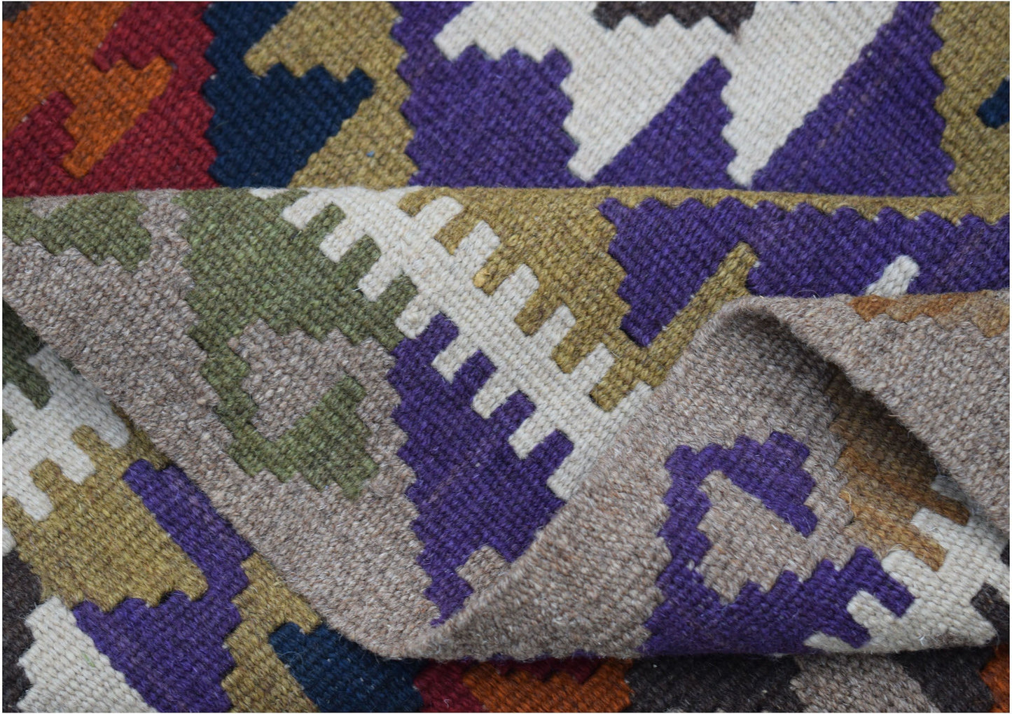 A handmade Afghan Maimana kilim featuring a geometric pattern in vibrant wool colors.