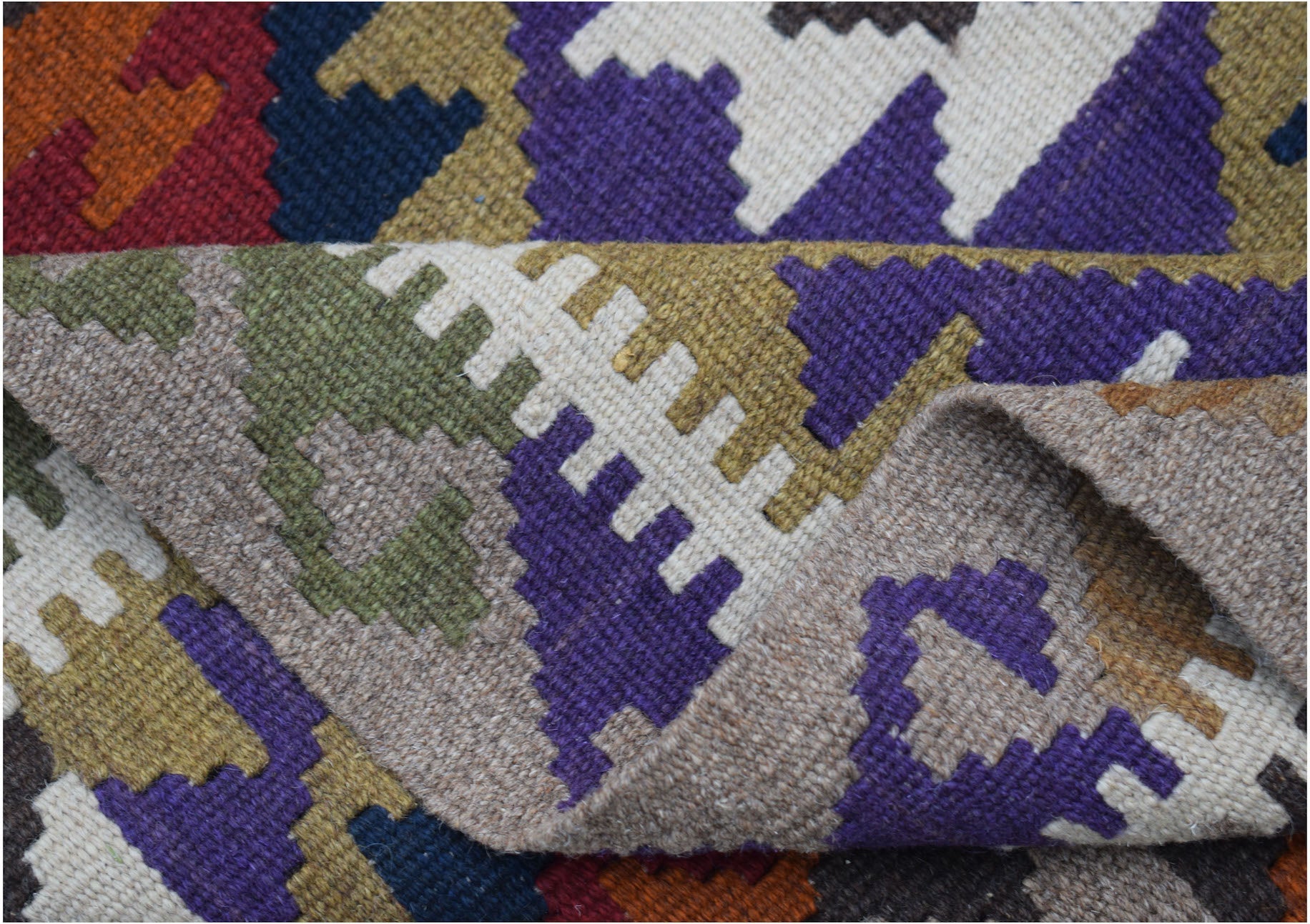 A handmade Afghan Maimana kilim featuring a geometric pattern in vibrant wool colors.