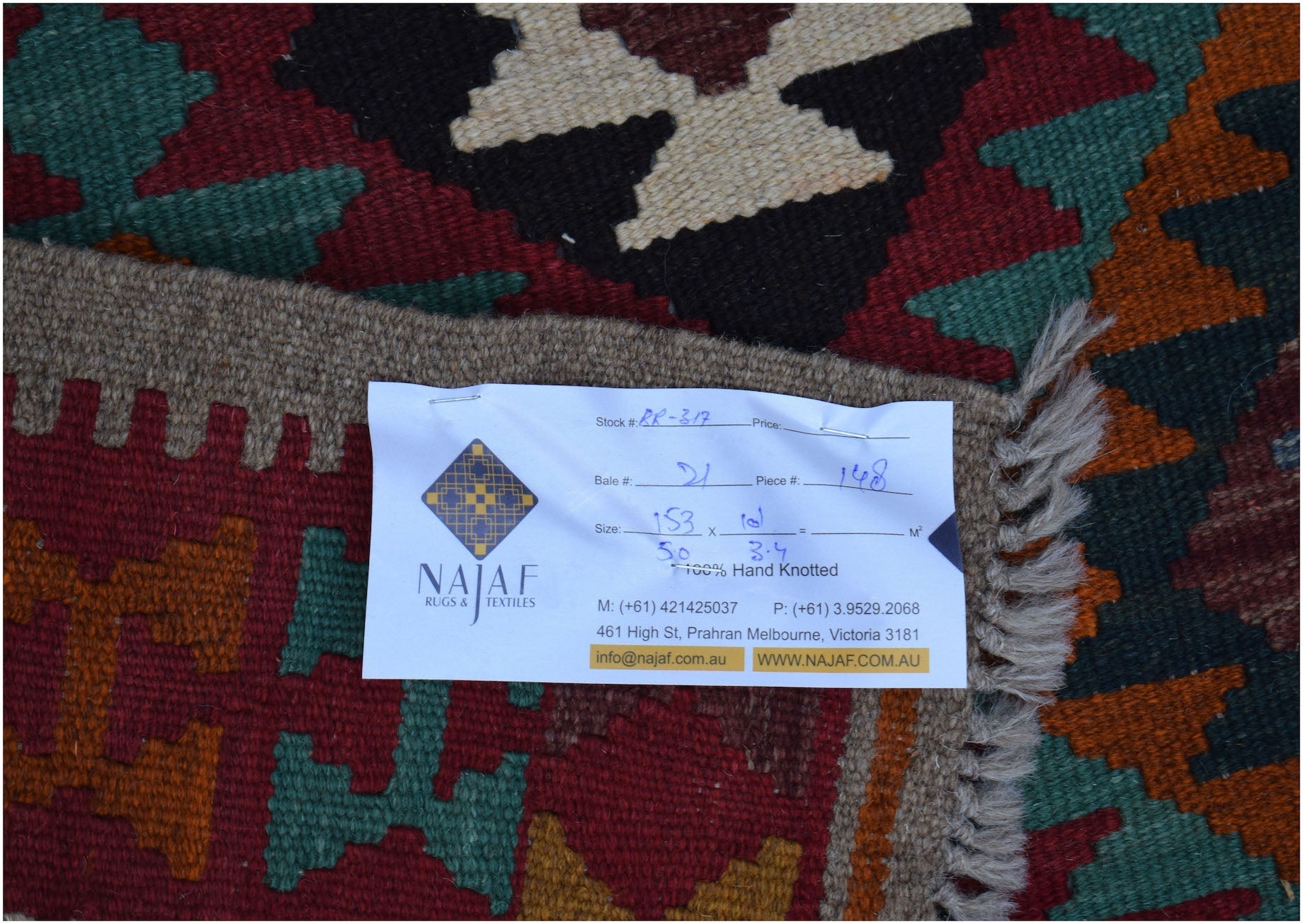 A handwoven Afghan Maimana kilim featuring a geometric pattern in red, green, and cream wool.