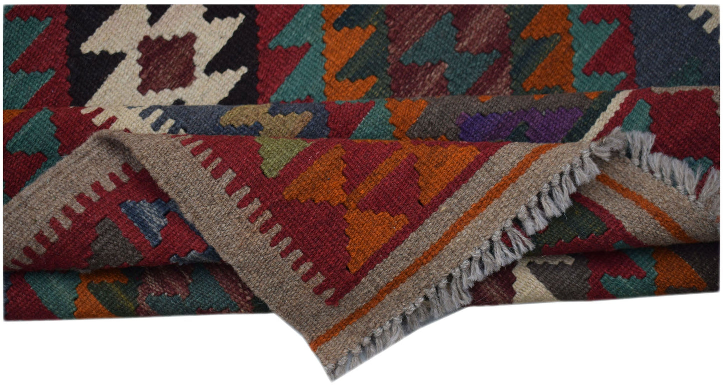 A handmade Afghan Maimana kilim rug featuring a geometric pattern in rich, multicolored wool.