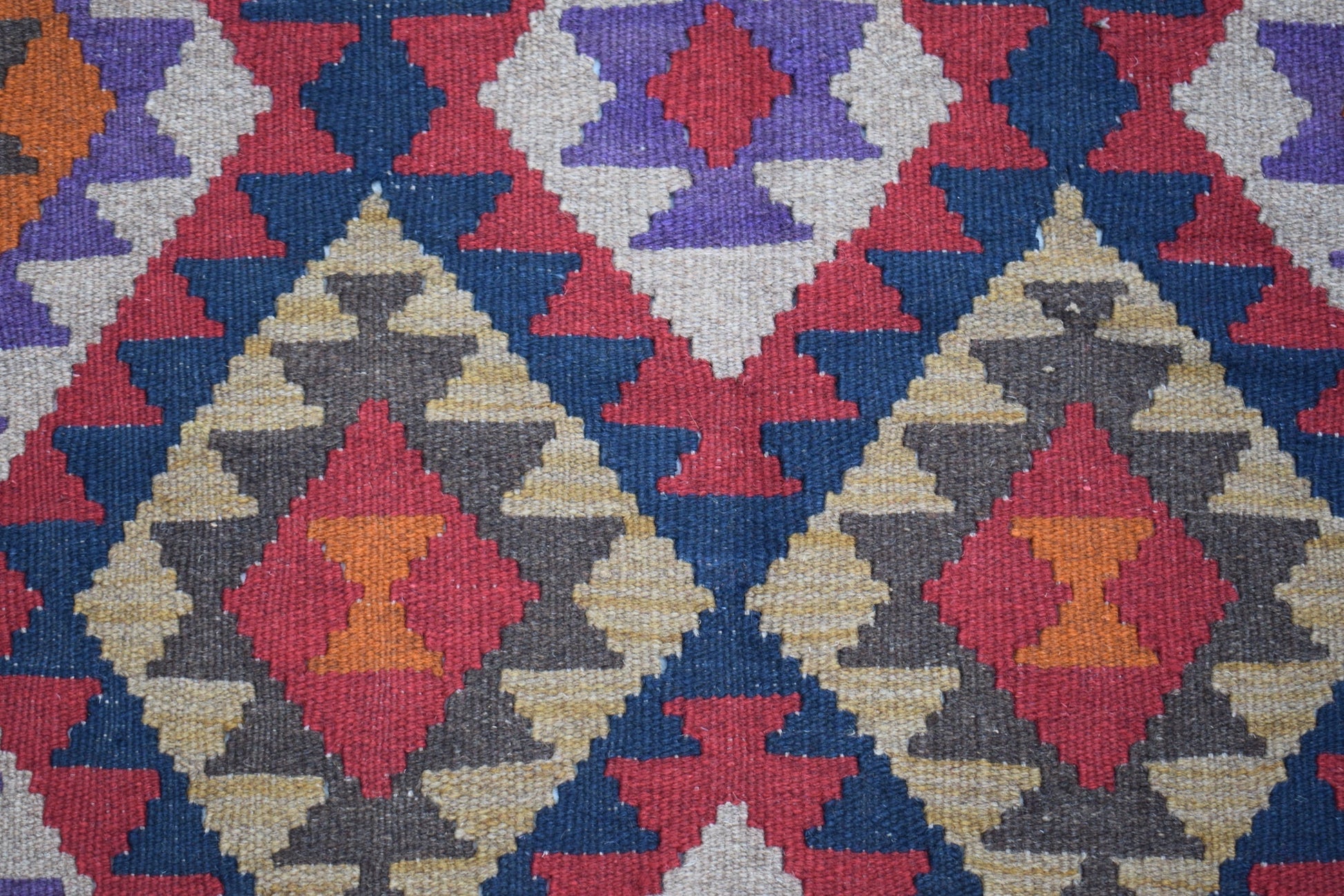 Handwoven Afghan Maimana kilim featuring a geometric diamond pattern in red, blue, and tan wool.