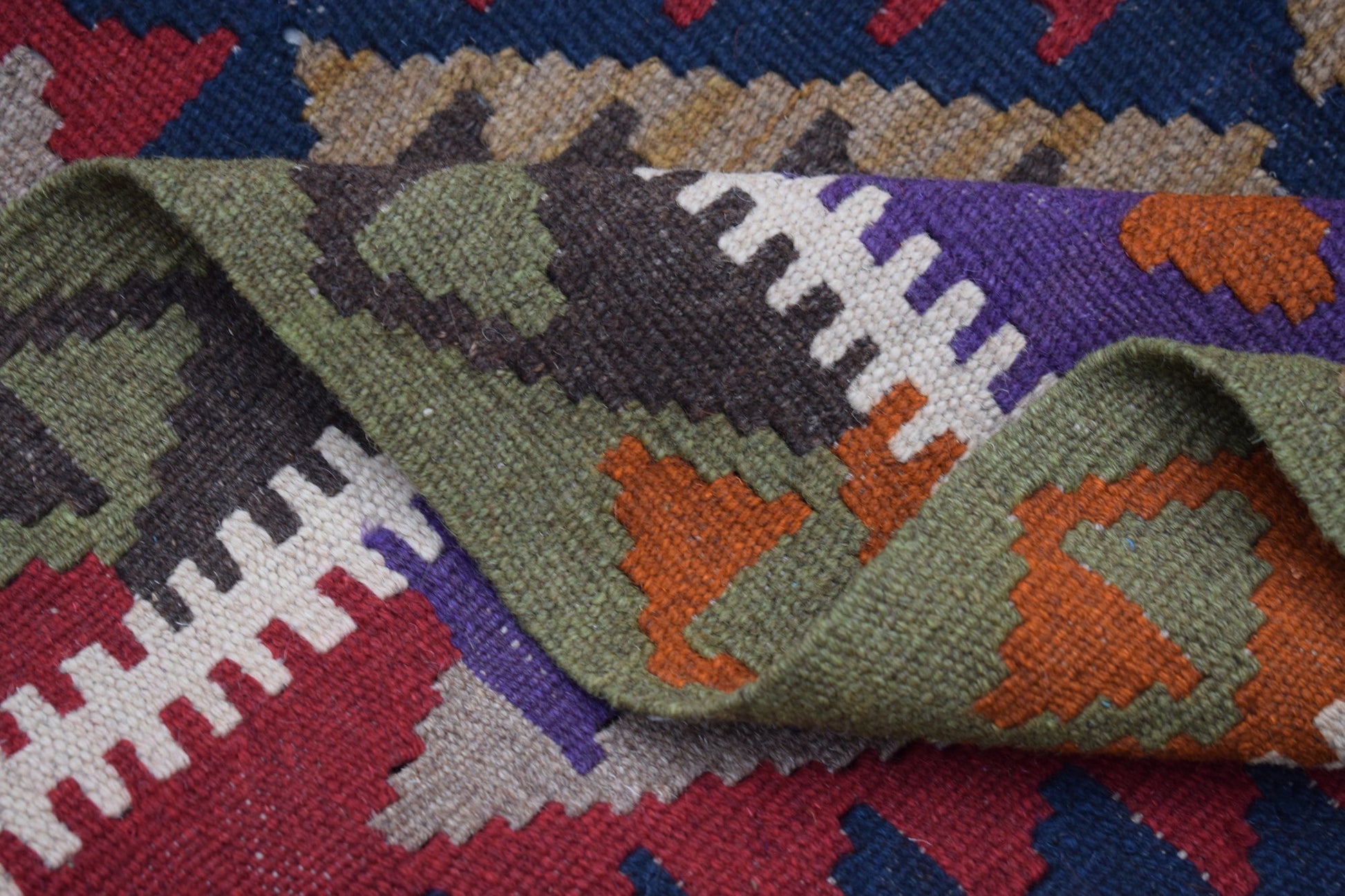 A handmade Afghan Maimana kilim rug featuring a geometric pattern in vibrant wool colors.