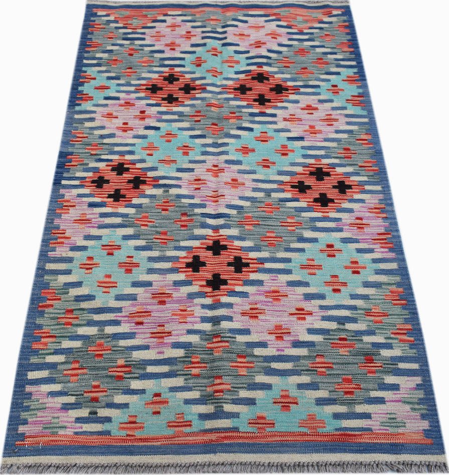 Handwoven Afghan Maimana kilim rug featuring a geometric pattern in blue, pink, and orange.