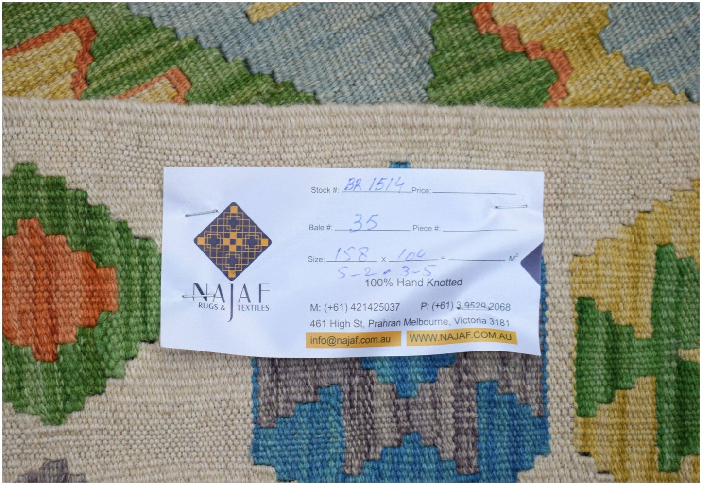 An Afghan Maimana kilim featuring a geometric pattern in green, yellow, orange, and blue tones.