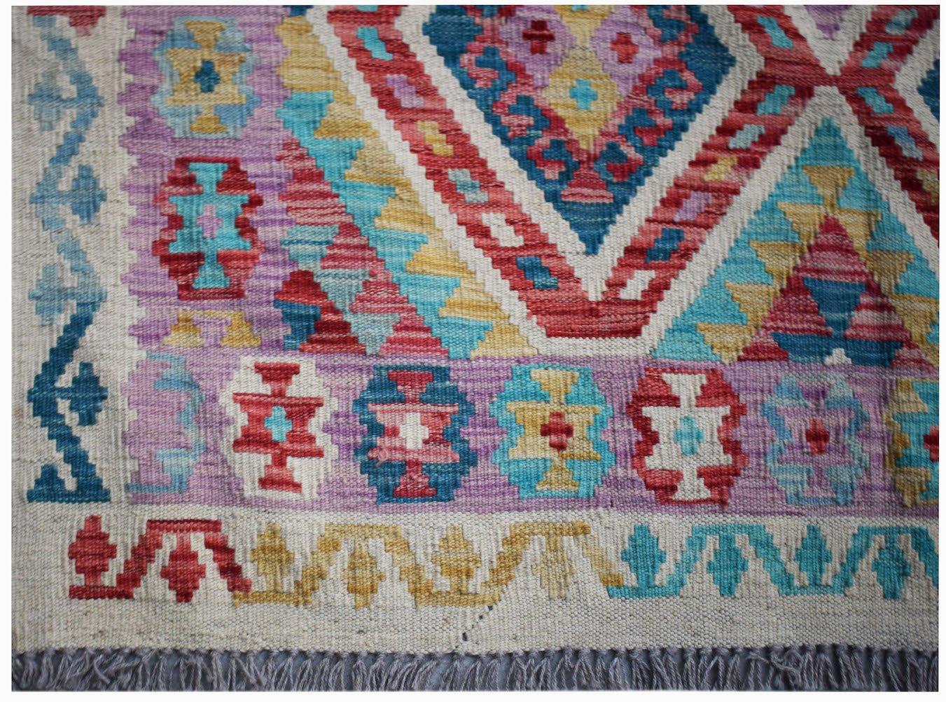 Handwoven Afghan Maimana kilim rug featuring a colorful geometric pattern on a flat wool weave.