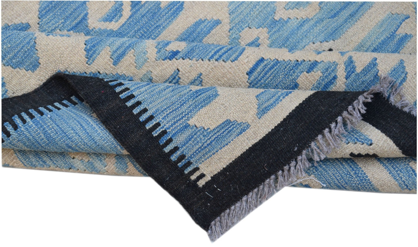 A handwoven Afghan Maimana kilim rug featuring a blue and cream geometric pattern with fringe.