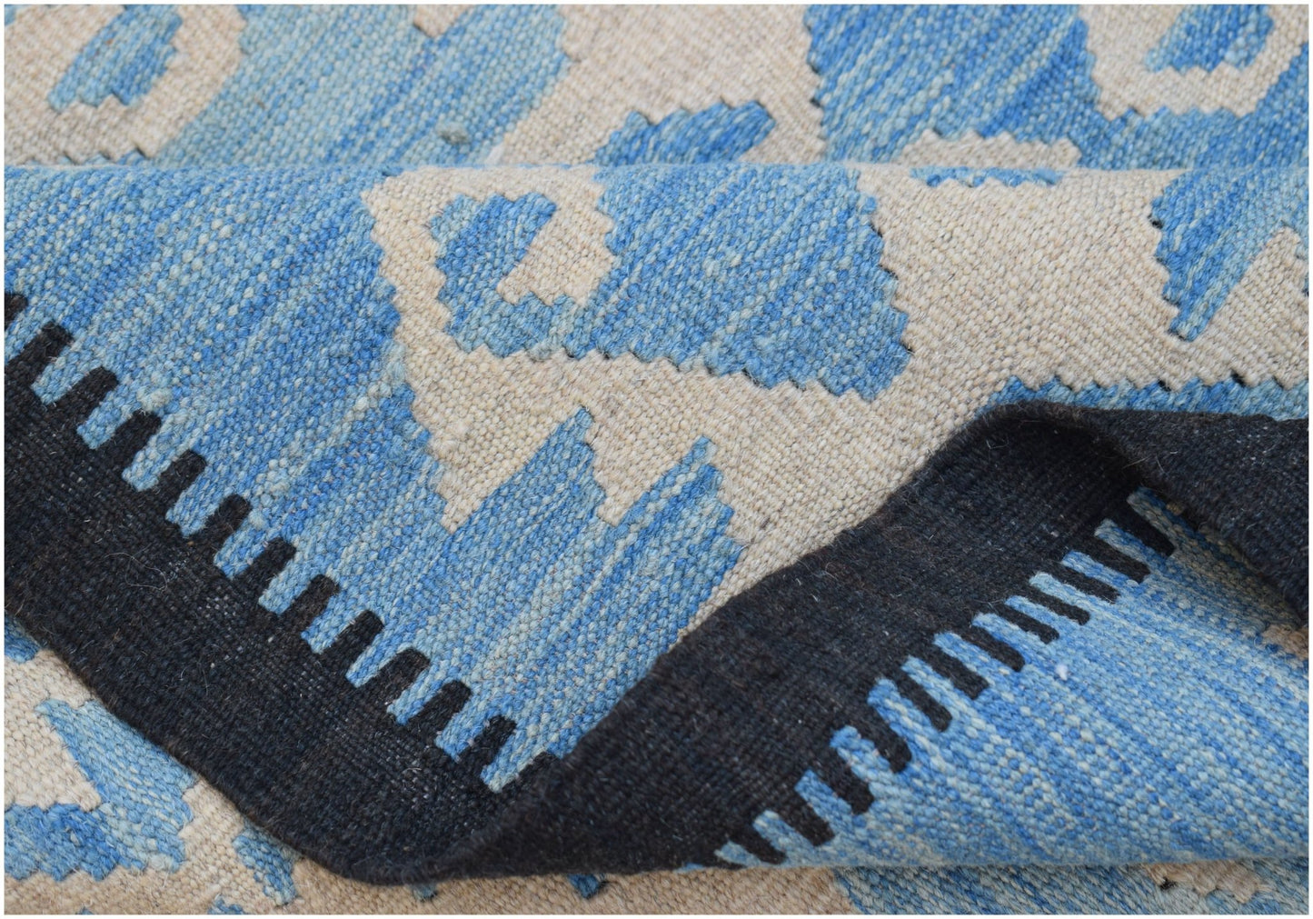 A handmade Afghan Maimana kilim featuring a blue and cream geometric pattern with a black border.