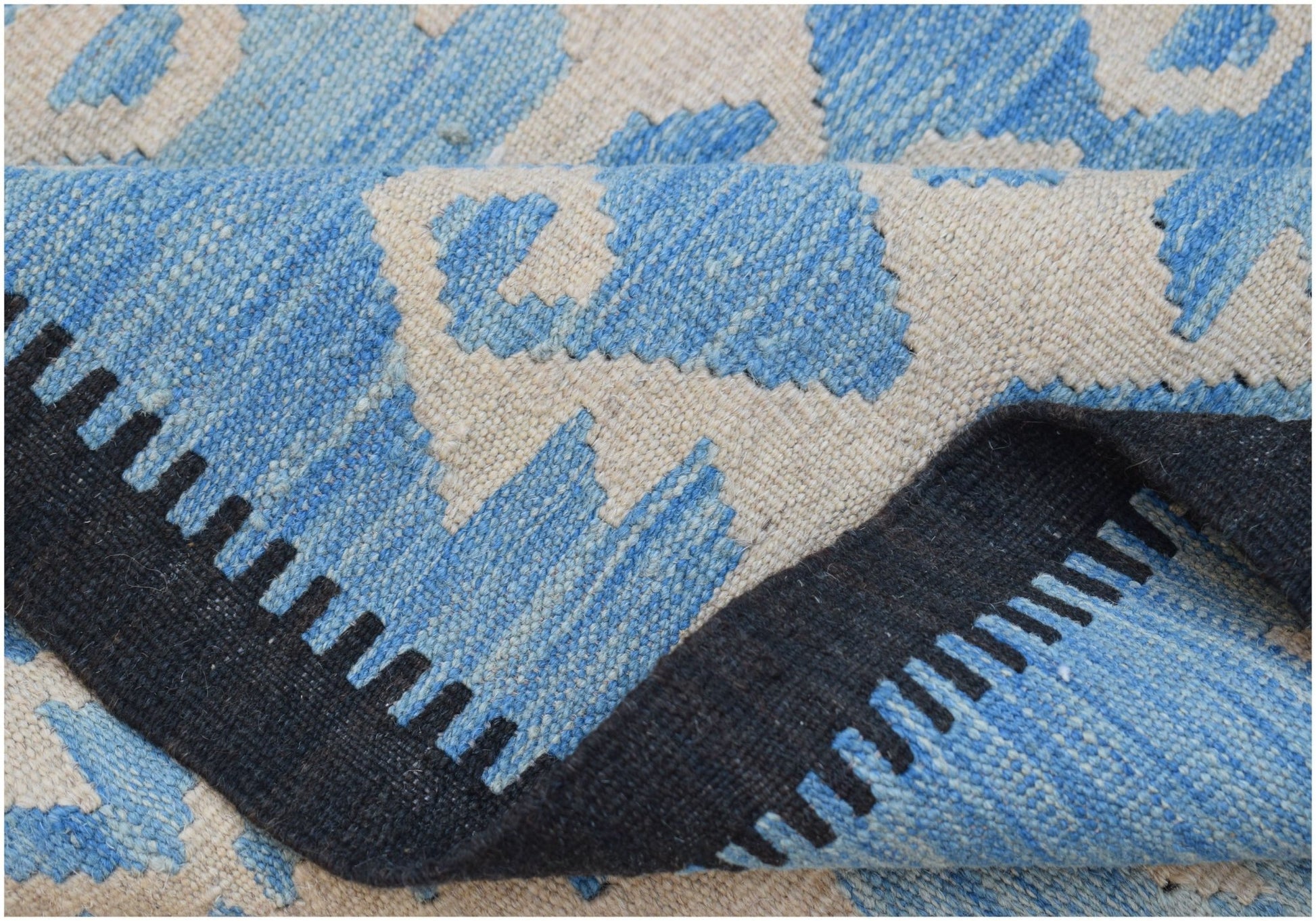 A handmade Afghan Maimana kilim featuring a blue and cream geometric pattern with a black border.