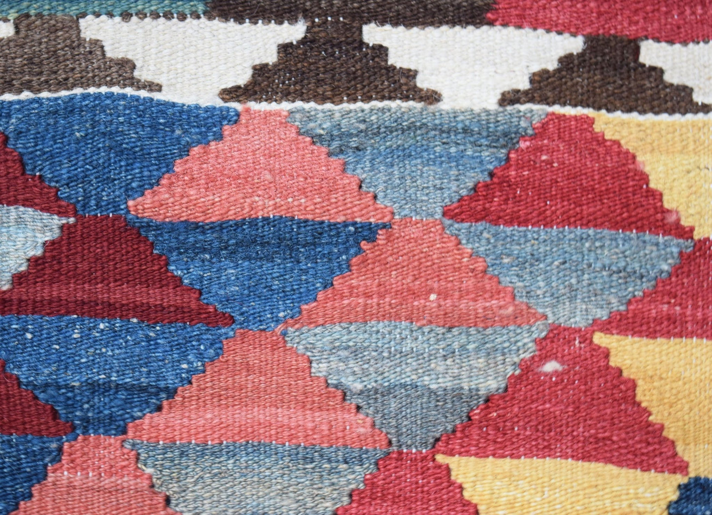 A handwoven Afghan Maimana kilim featuring a geometric pattern of red, blue, and yellow diamonds.
