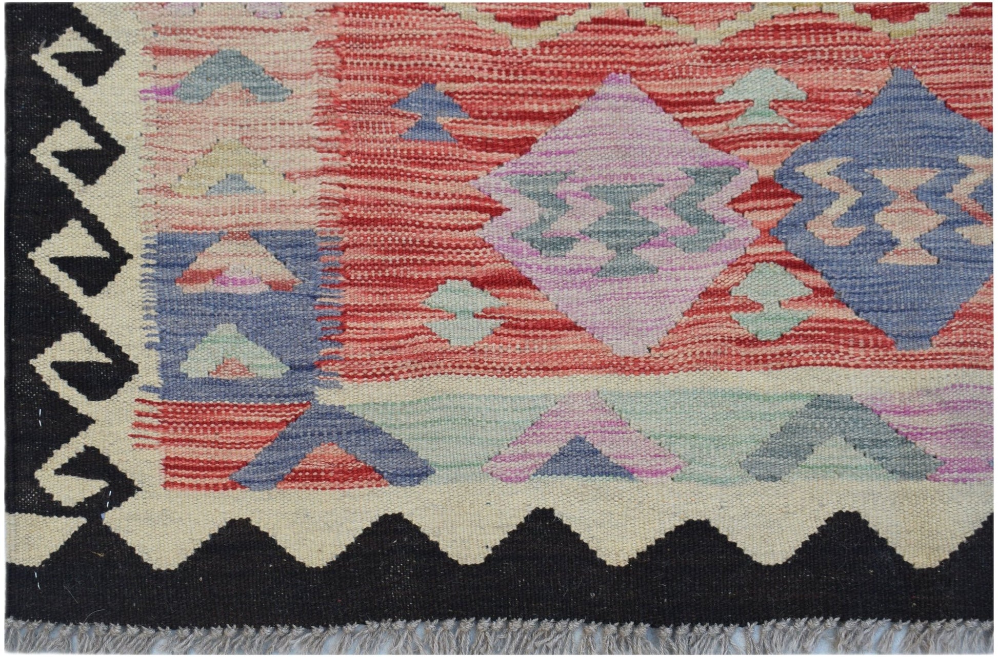 Handwoven Afghan Maimana kilim featuring geometric patterns in red, blue, and purple wool.