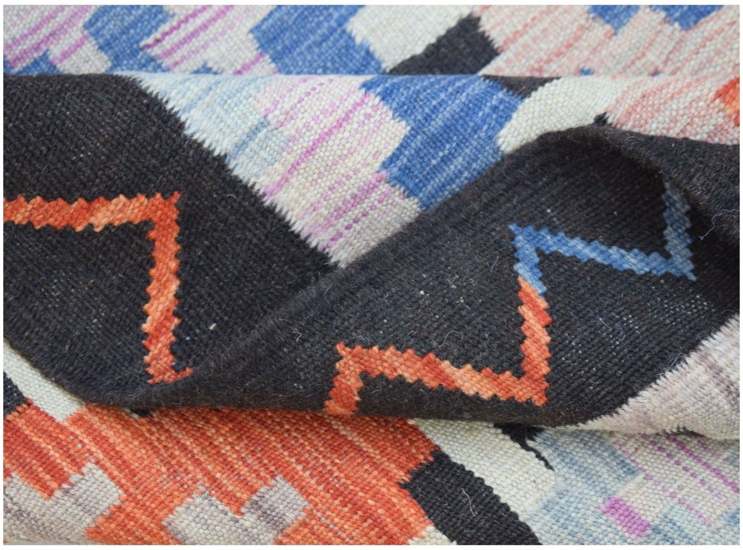 A handmade Afghan Maimana kilim rug featuring a geometric pattern in black, orange, and blue.