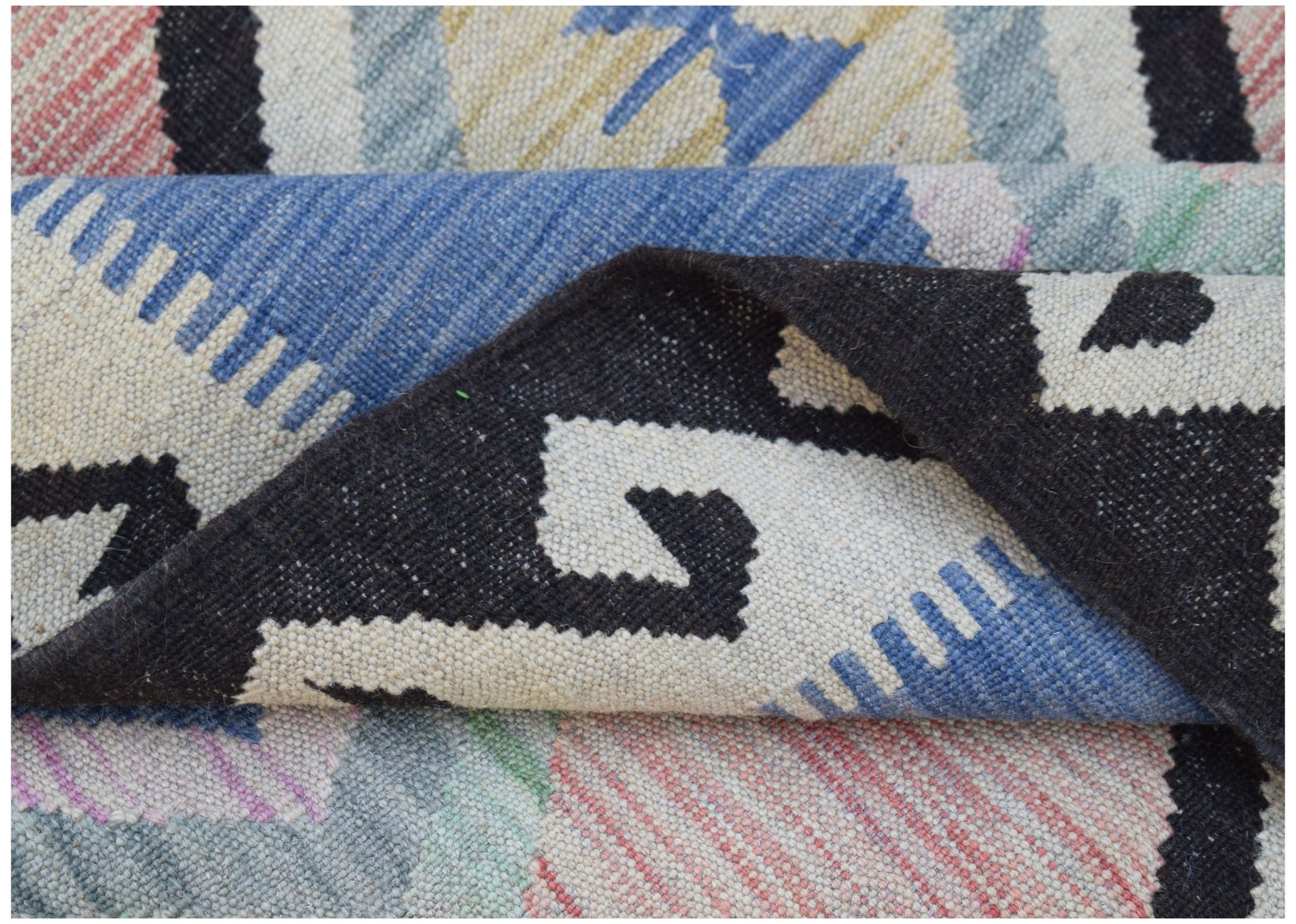 A handwoven Afghan Maimana kilim featuring a geometric pattern in blue, black, and cream wool.
