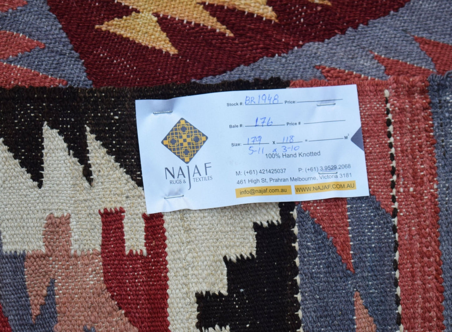 An Afghan Maimana kilim rug featuring a geometric pattern in shades of red, grey, and cream.