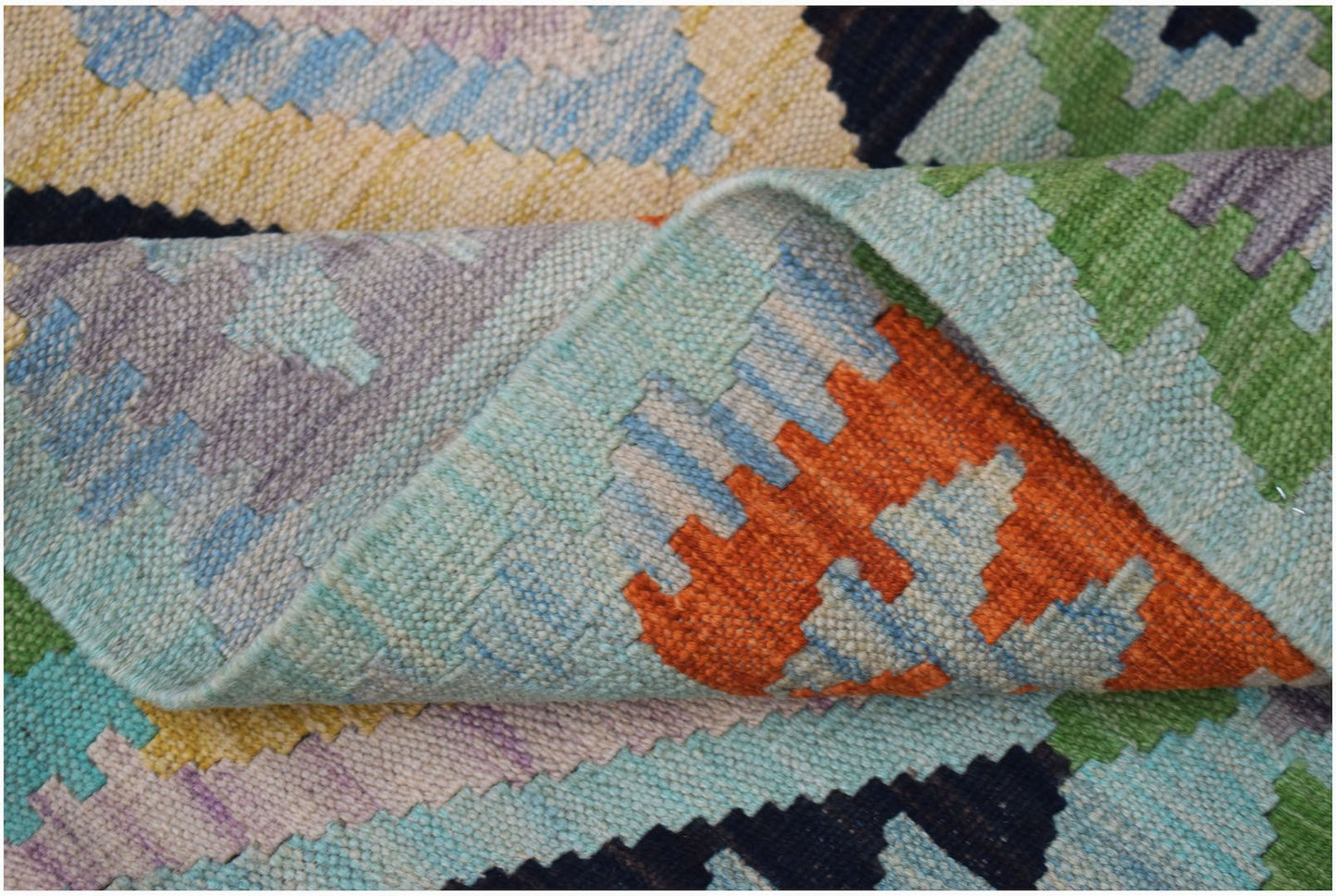 A handmade Afghan Maimana kilim rug featuring a colorful geometric pattern in a flatweave texture.